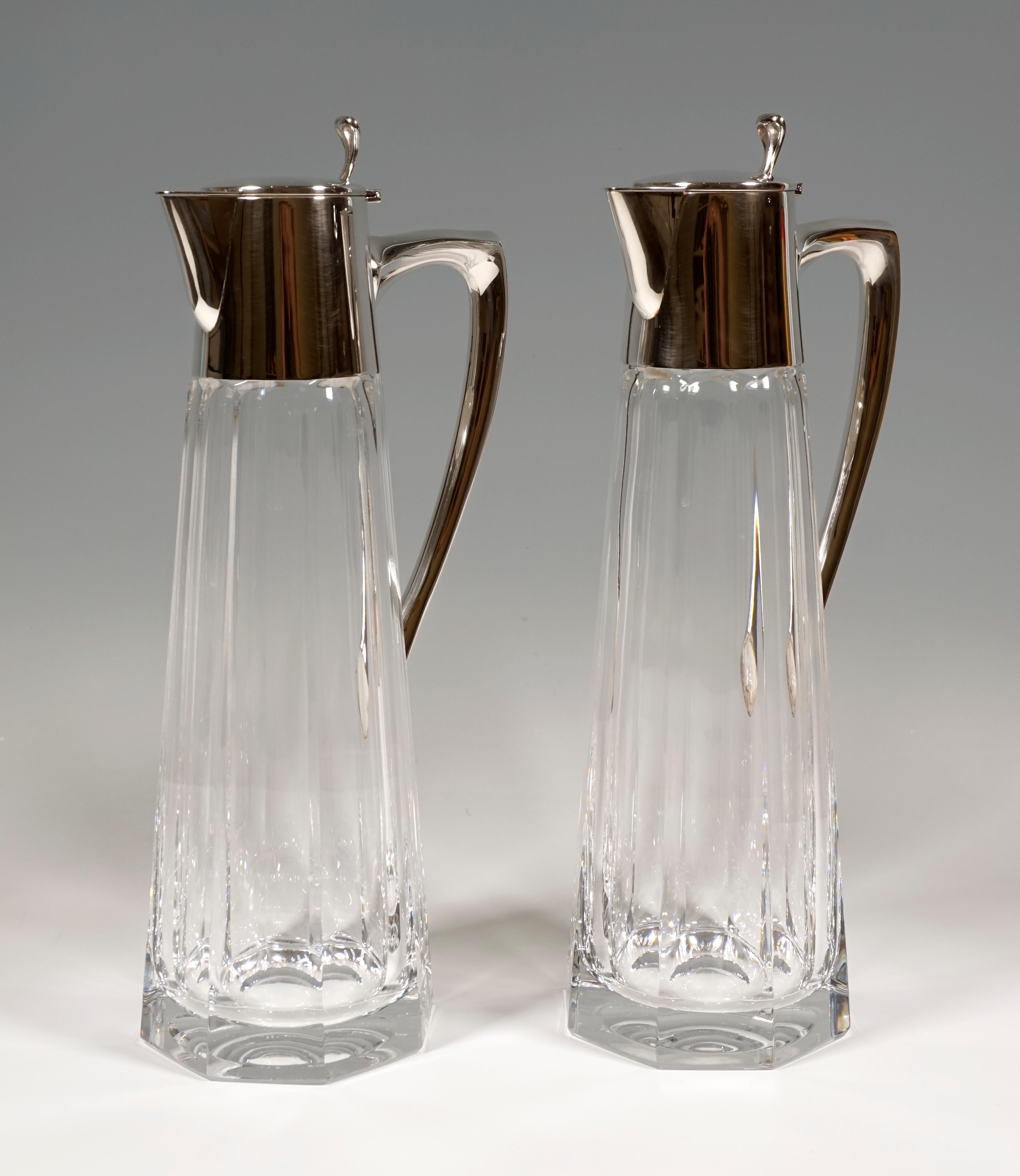 Pair of glass carafes made of faceted clear glass on an octagonal stand, silver mount with hinged lid with thumb rest and elegantly curved handle.

Dimensions:
Height 31.0 cm / 12.20 in
Width 13.0 cm / 5.11 in
Depth 9.5 cm / 3.74