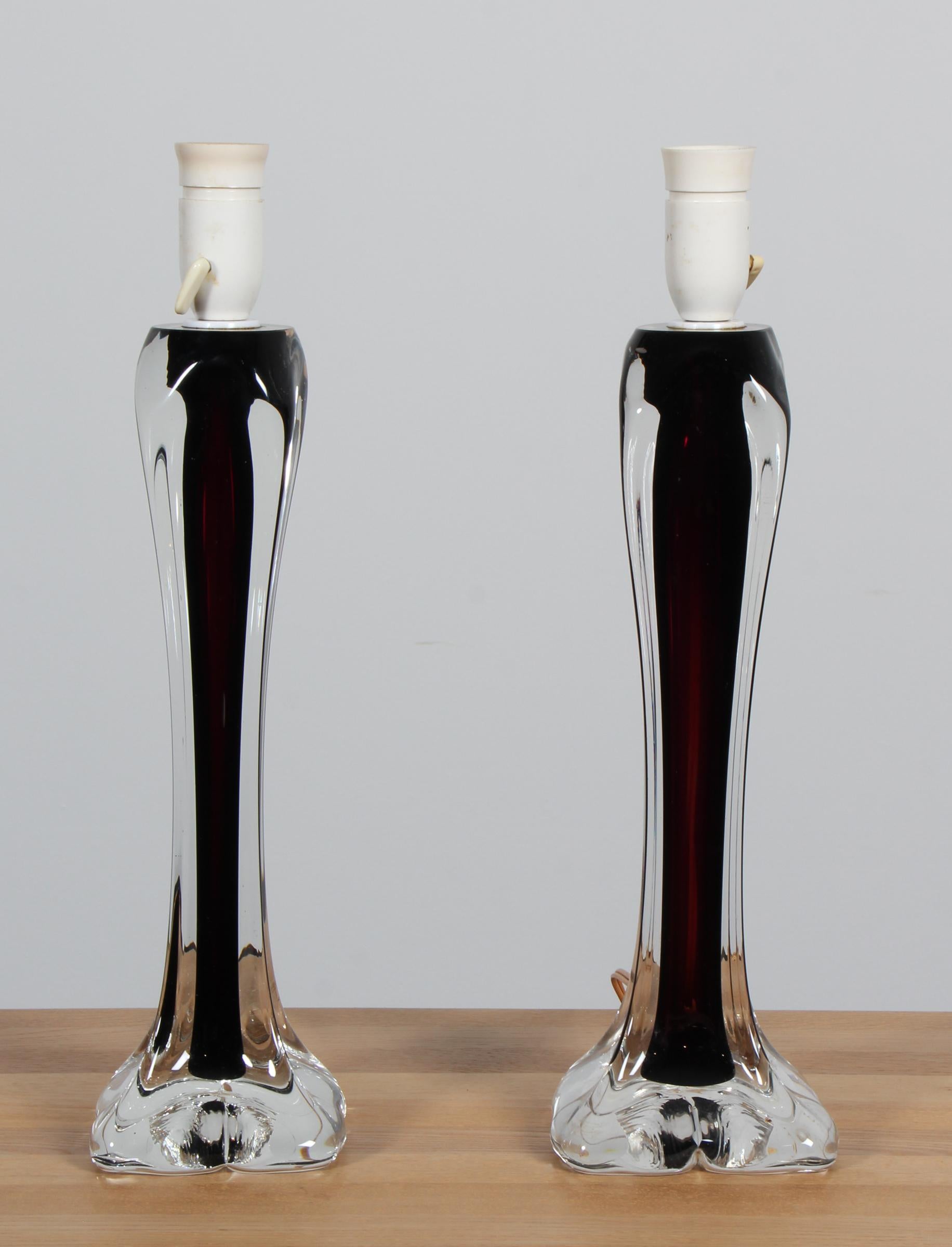 Pair of vintage table lamps, designed by Paul Kedelv for Flygfors in the 1960s, features a coloured and clear glass base. The base is elegantly elongated, tapering to a rounded bottom with smooth, flowing lines that highlight the craftsmanship of