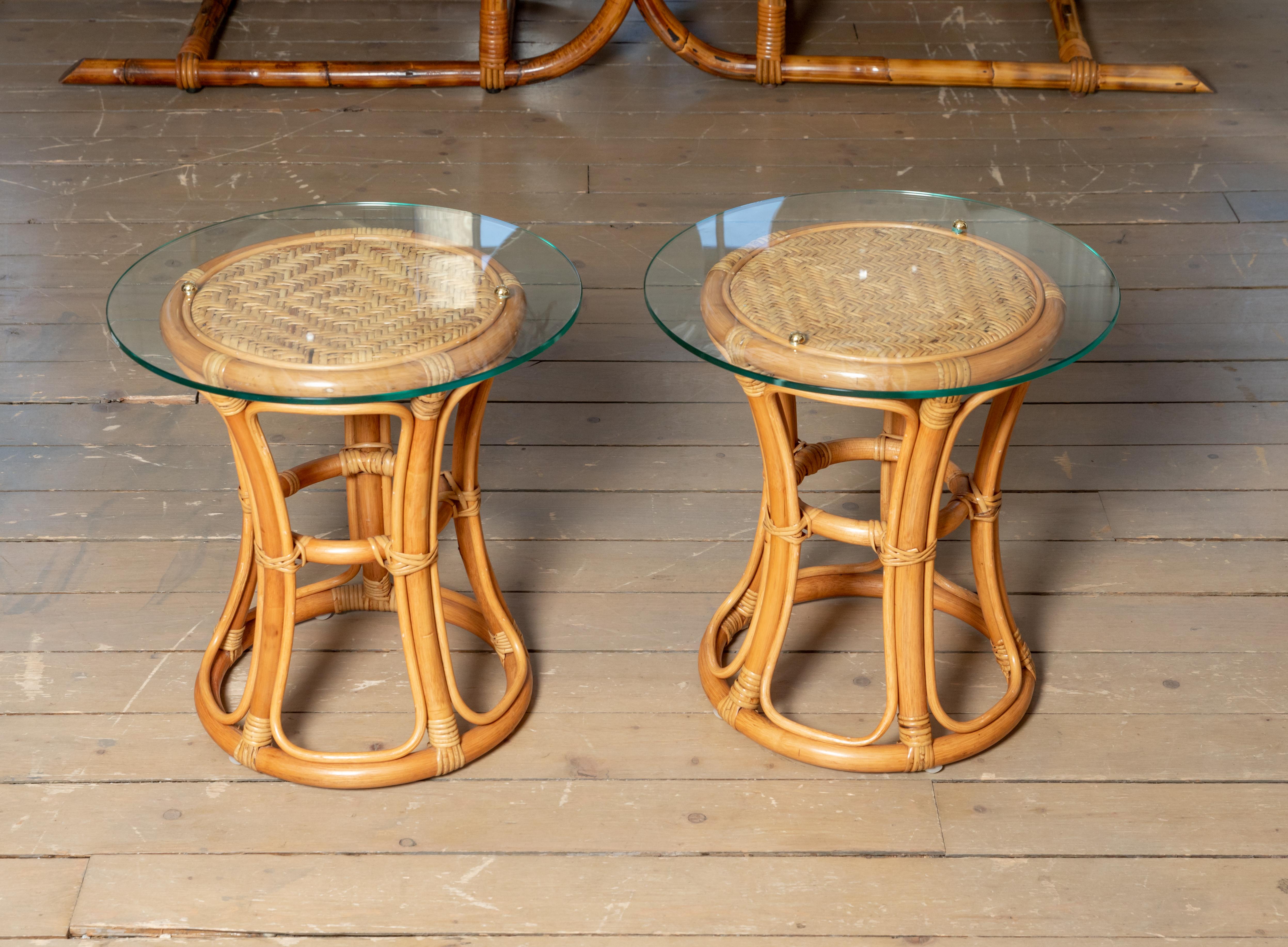Pair of glass top rattan and woven wick tables with brass details.