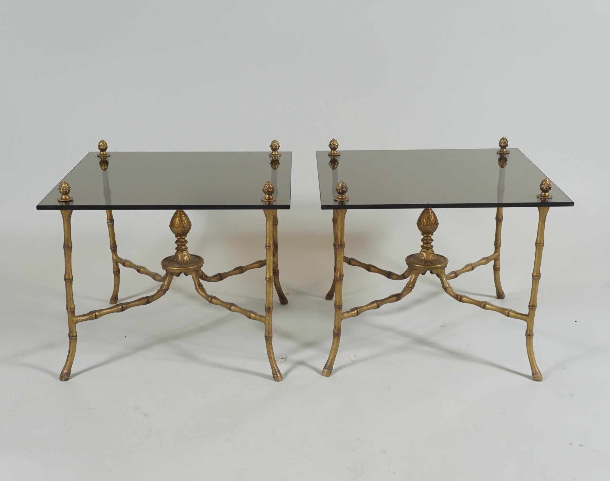 Pair of glass topped side or end tables in the renaissance style with gilded metal bases.