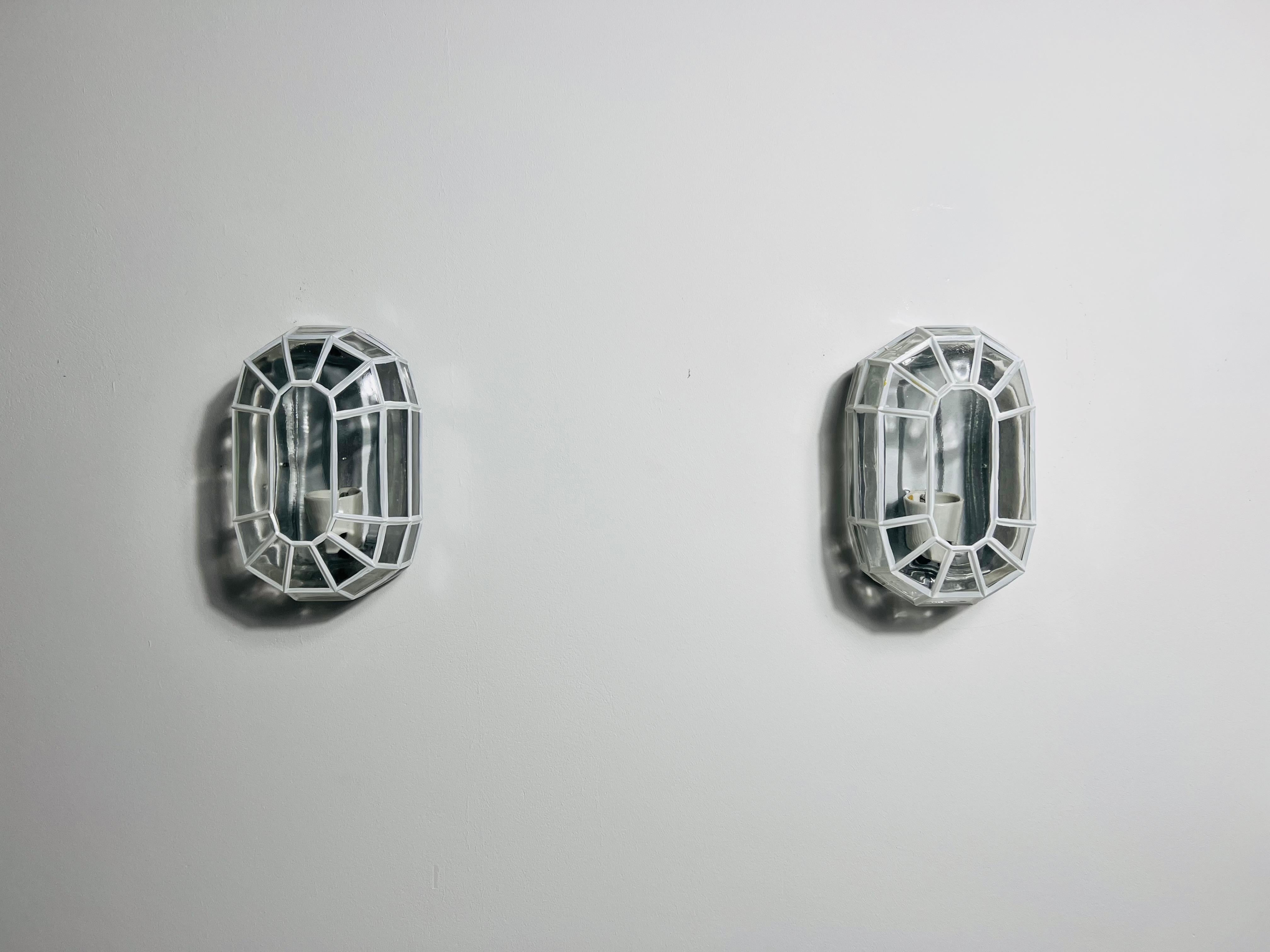 This pair of distinguished Limburg wall lamps, crafted in the 1960s, exemplifies the superior quality and precision of German workmanship. The lamp is elegantly designed with a iron design glass shade, which is securely rotated into the frame,