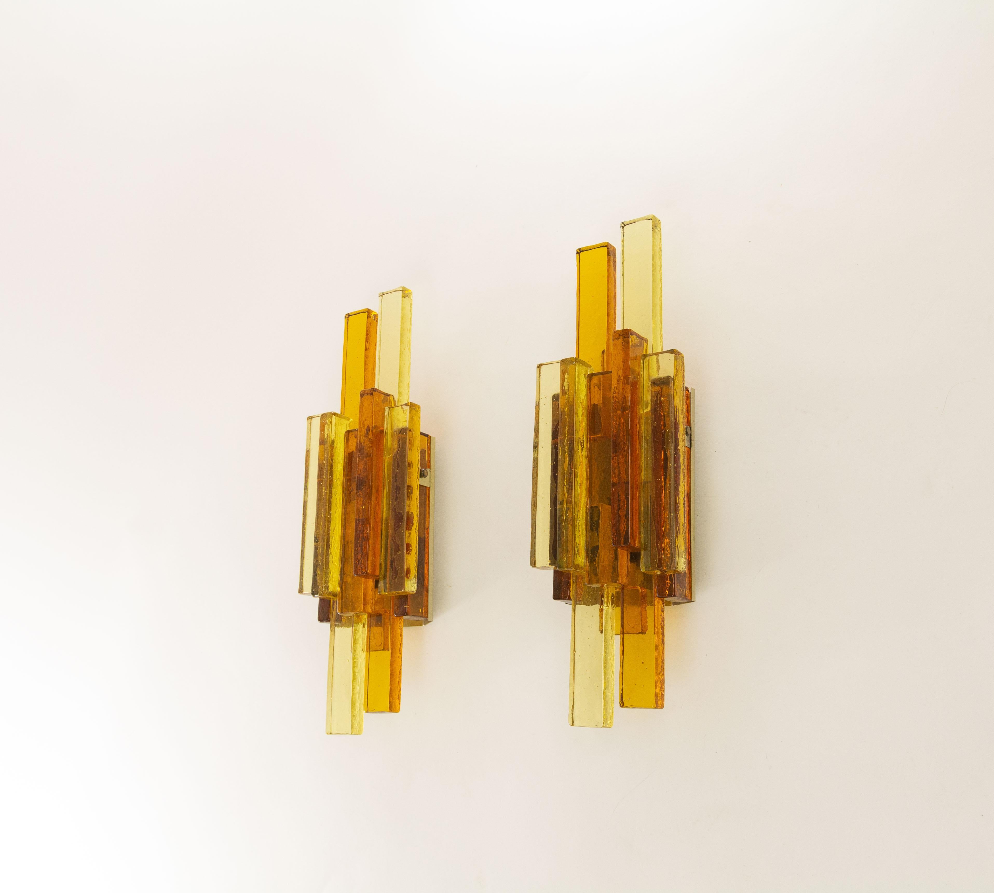 A pair of glass wall lamps No. 5104 designed by Svend Aage Holm Sørensen for his own company, Holm Sørensen & Co.

Beautifully designed with golden and amber colored glass, granting the lamps a classy appearance. The original company branding is