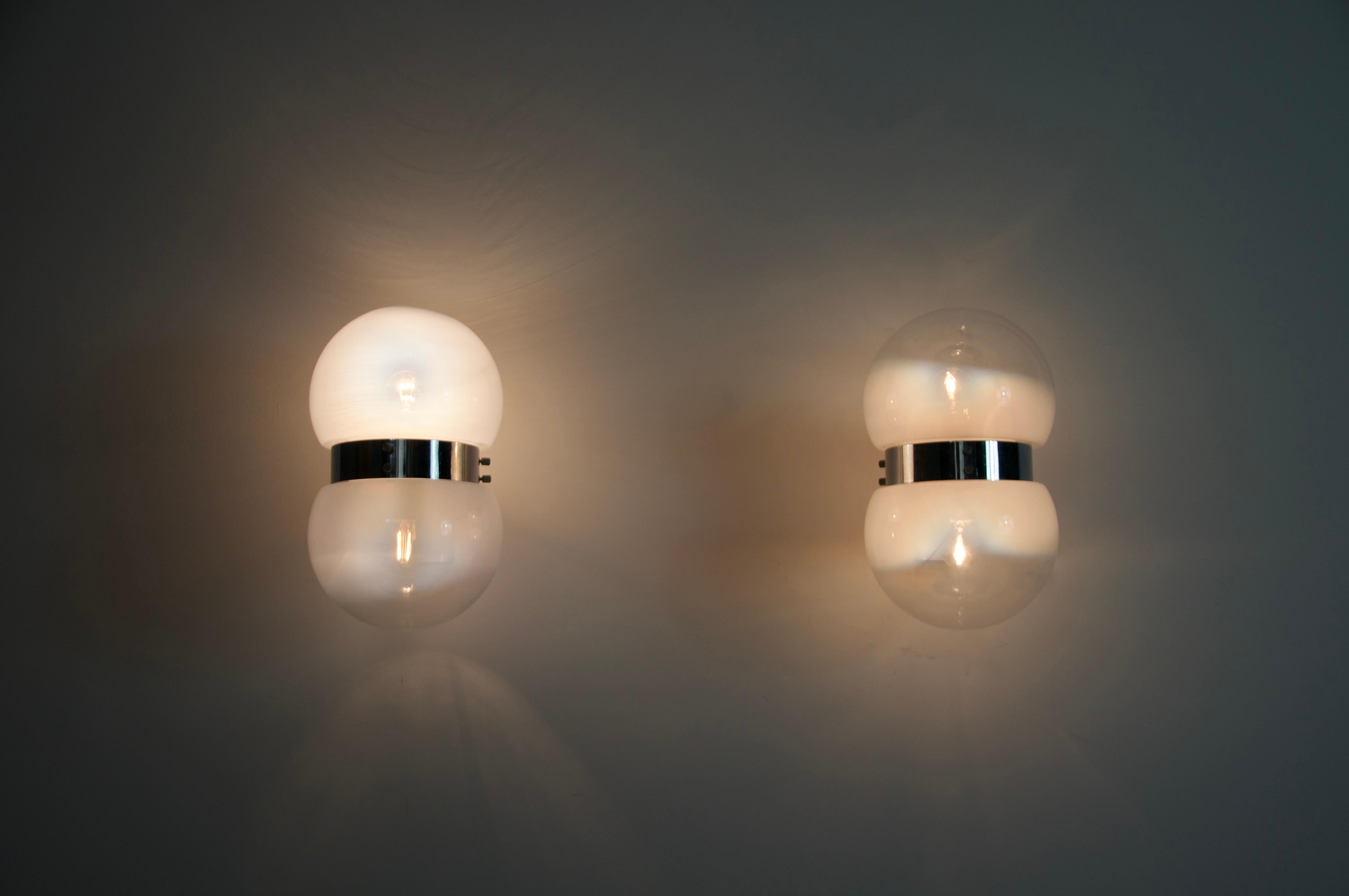 Dieses Paar Wandleuchten, das Sergio Mazza in den 1960er Jahren für Artemide entworfen hat, verleiht Ihrem Raum einen raffinierten Hauch von italienischem Modernismus. Mit ihrem ikonischen doppelten Glaskugeldesign und einem verchromten