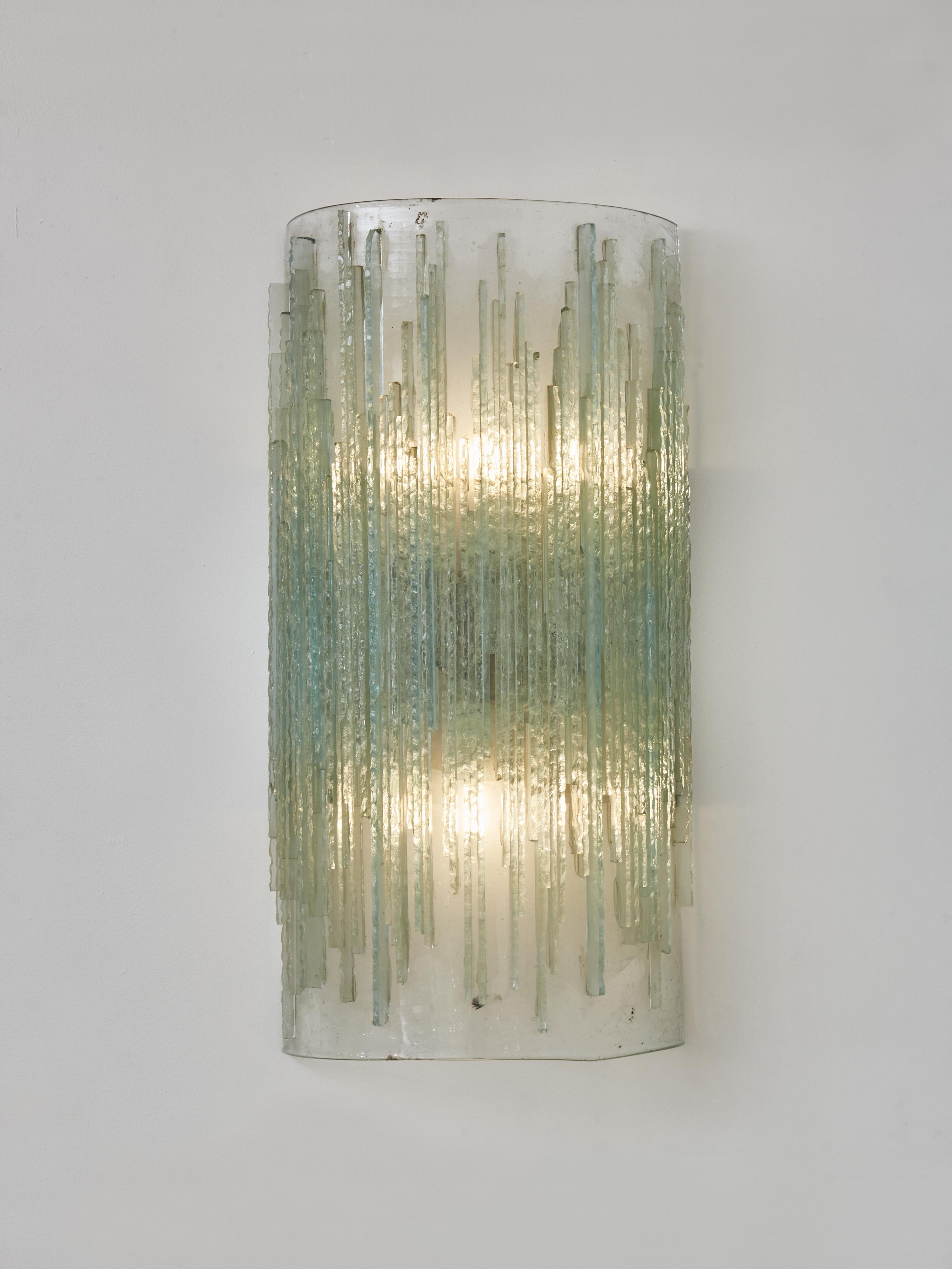 Pair of wall sconces made of one large curved glass piece on which are attached raw edges glass strips diffusing the light.