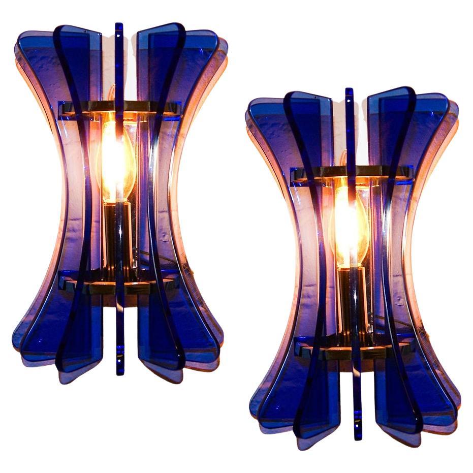 Pair of Murano glass wall sconces by Veca Italy.
Unusually shaped in the form of a bunched figure 8.
Deep blue transparent glass slats, secured on a chromed steel frame, with 2 light bulb carrier to each sconce.
Very uniquely shaped and with vibrant