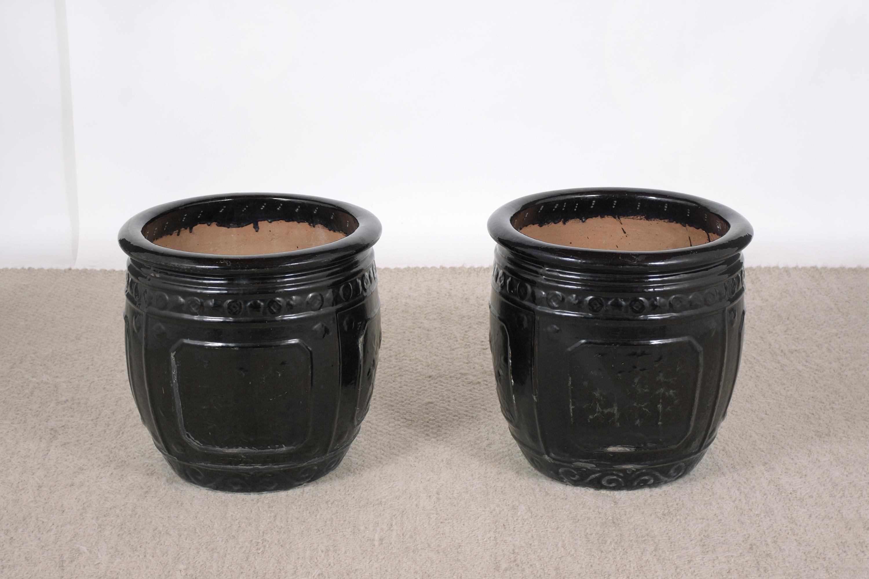 An extraordinary pair of large ceramic planters in good condition. This fabulous pair of garden planters feature a beautiful design accentuated moldings decorations around painted in black color with a beautiful glazed finish. Base diameter 16