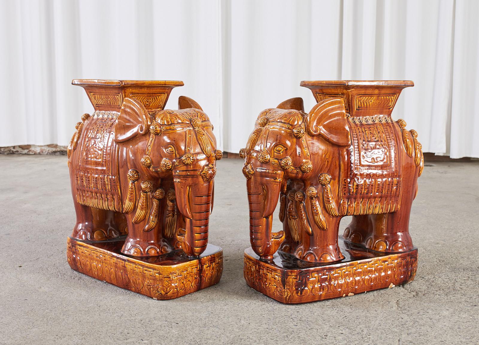 Charming pair of Chinese ceramic garden stool seats or drinks tables featuring a rich cognac glazed finish. Each elephant is depicted standing on an oval plinth with a caparisoned body. Beautifully crafted with an aged patina on the glaze having