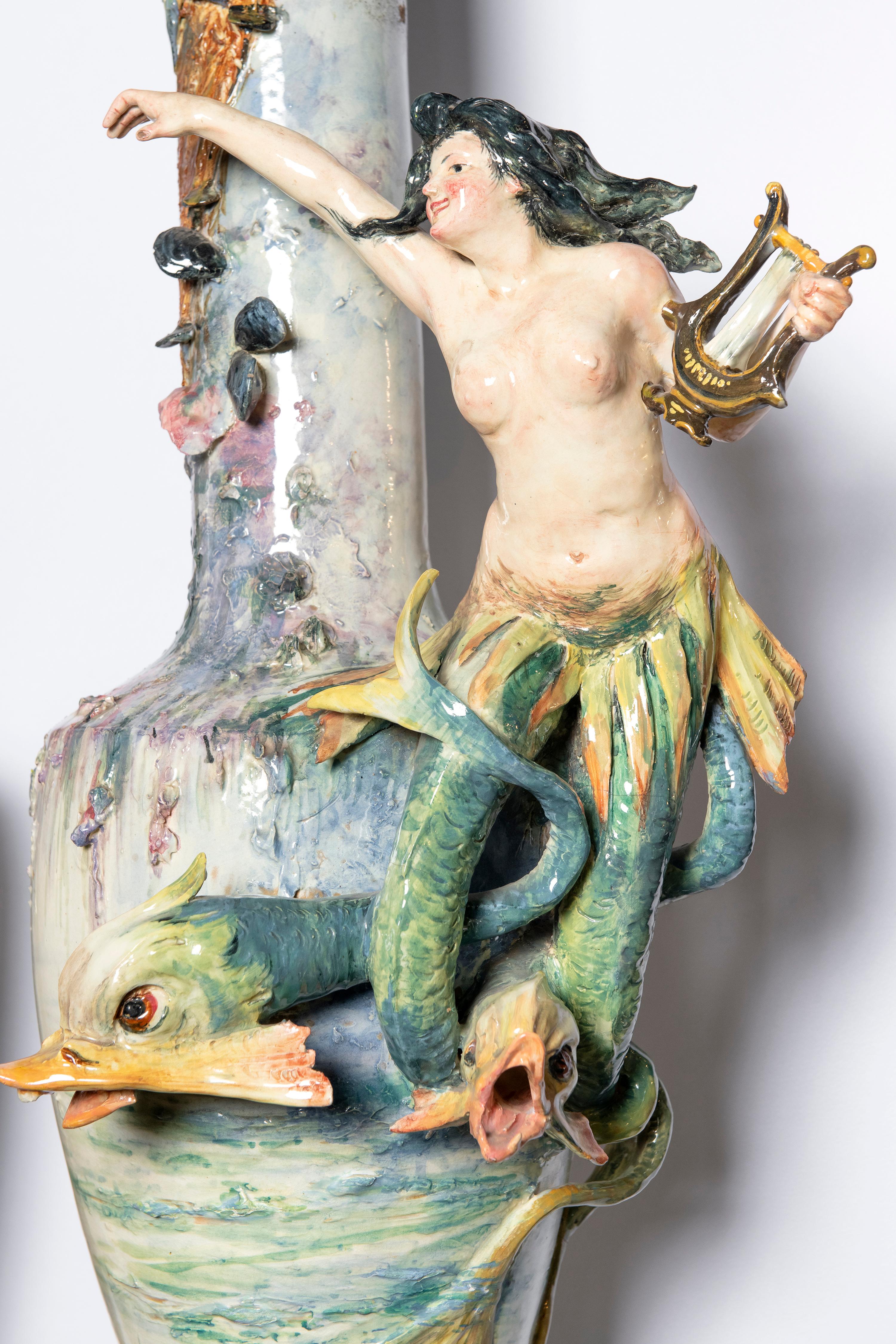Pair of glazed ceramic vases with wood base, France, late 19th century.
With mythology figures, Psyche with angels and Siren.
Measures: Ceramic vase height 100 cm.
Wood base height 53 cm.
Total piece height 153 cm.