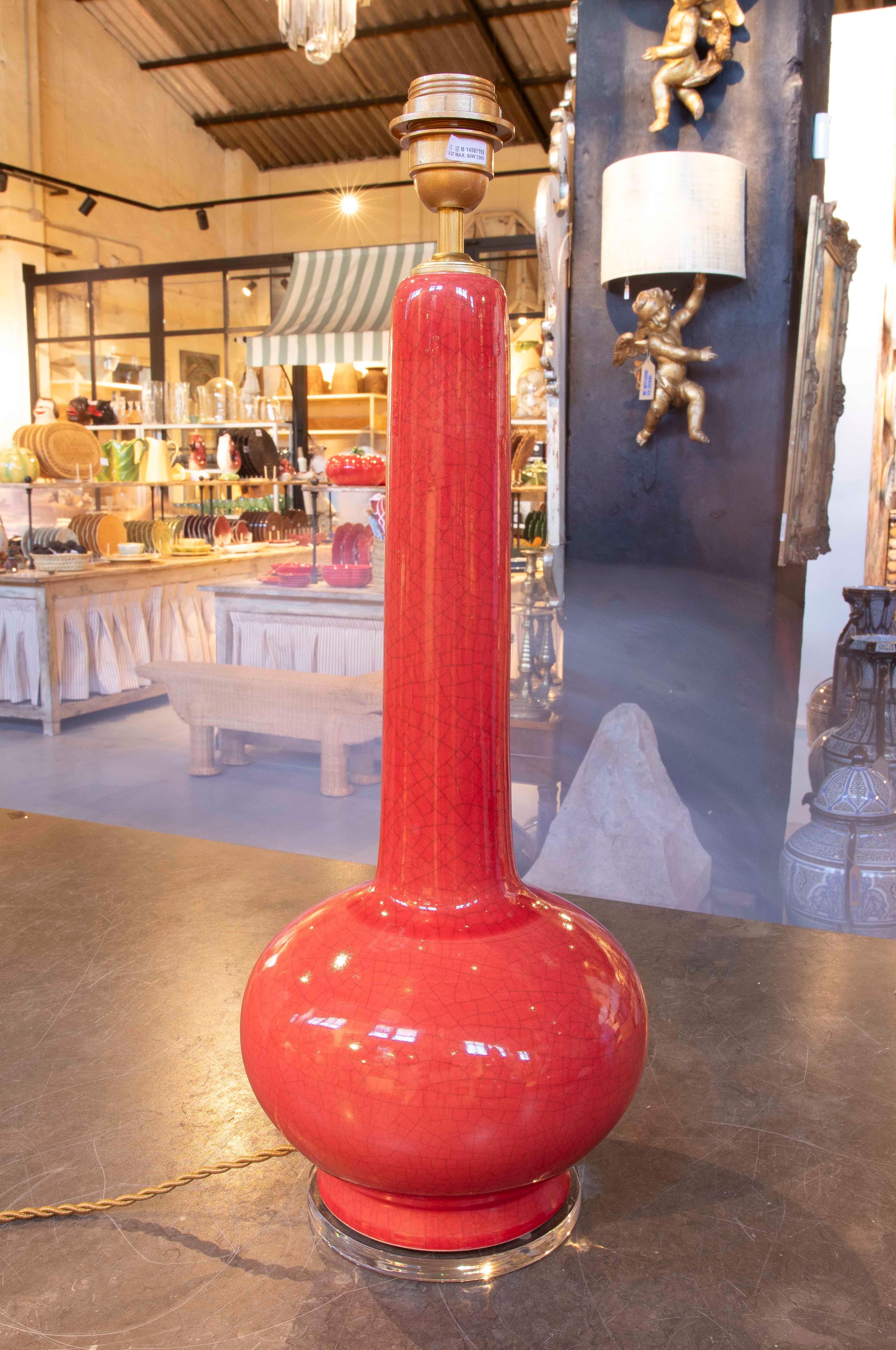 Un elegante par de lámparas de mesa de cerámica esmaltada en un intenso rojo coral con efecto craquelado, que añade textura y profundidad al acabado. La base globular y el diseño alargado del cuello recuerdan las formas orientales reinterpretadas en