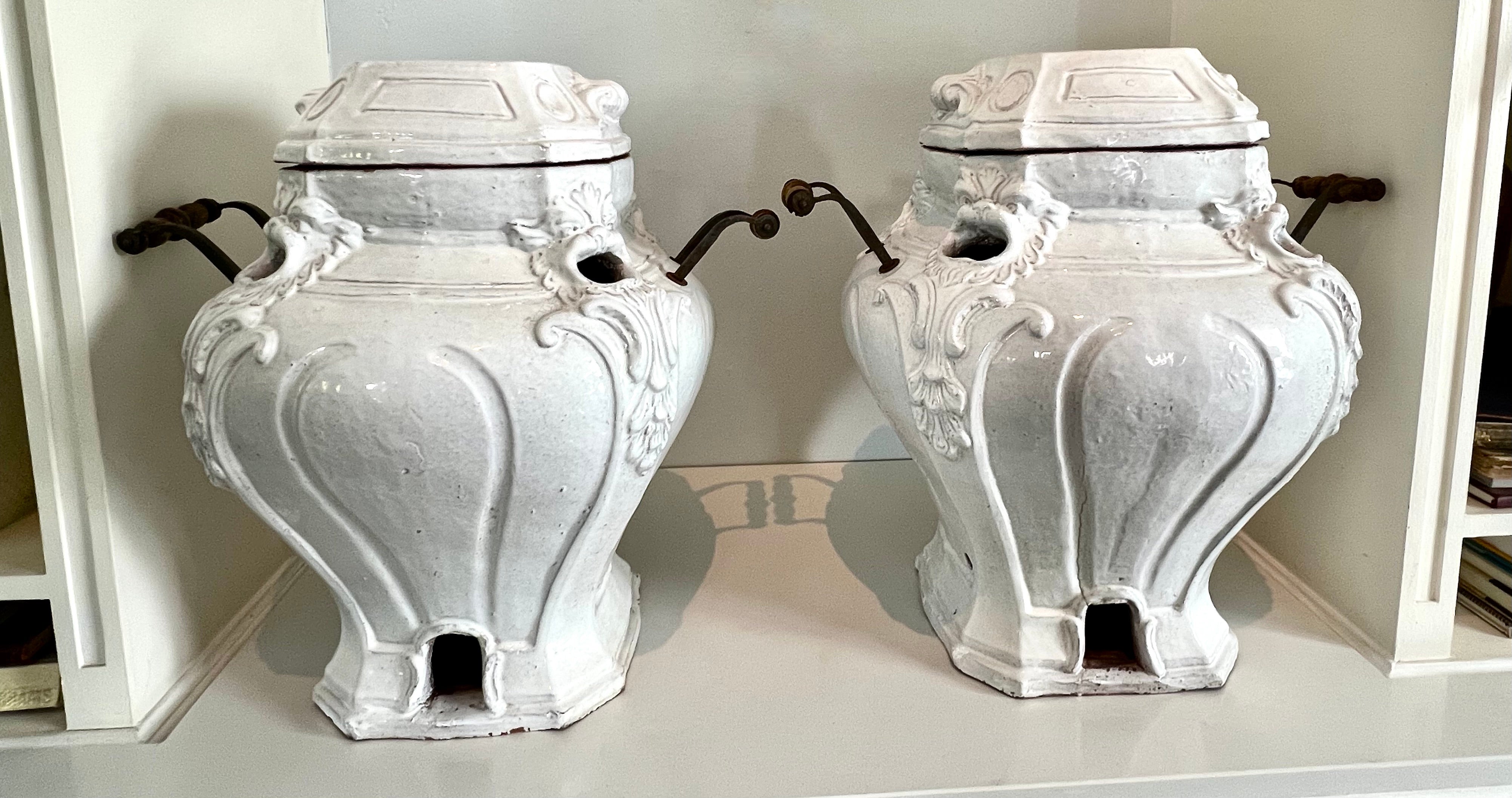 A unique pair of Glazed Terracotta planters or Urns with metal and wood handles and removable lid. The pair have a wonderful look with a opening on each corner with a carved dragon or foo face... the handles are unique in design - the lids are