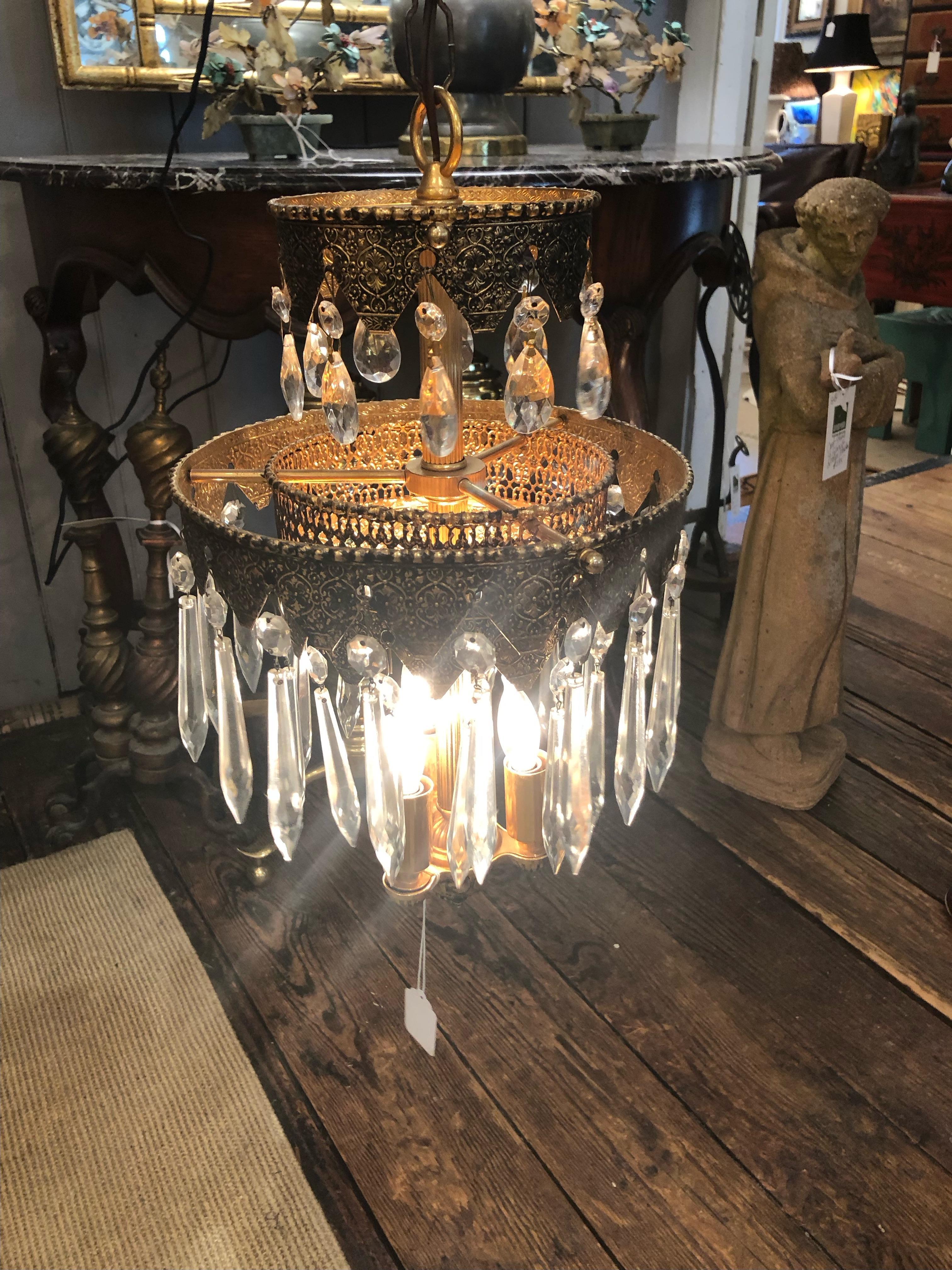 An art deco style pair of glam medium sized multi-tiered etched pot metal chandeliers having intricate decoration and lots of crystals.