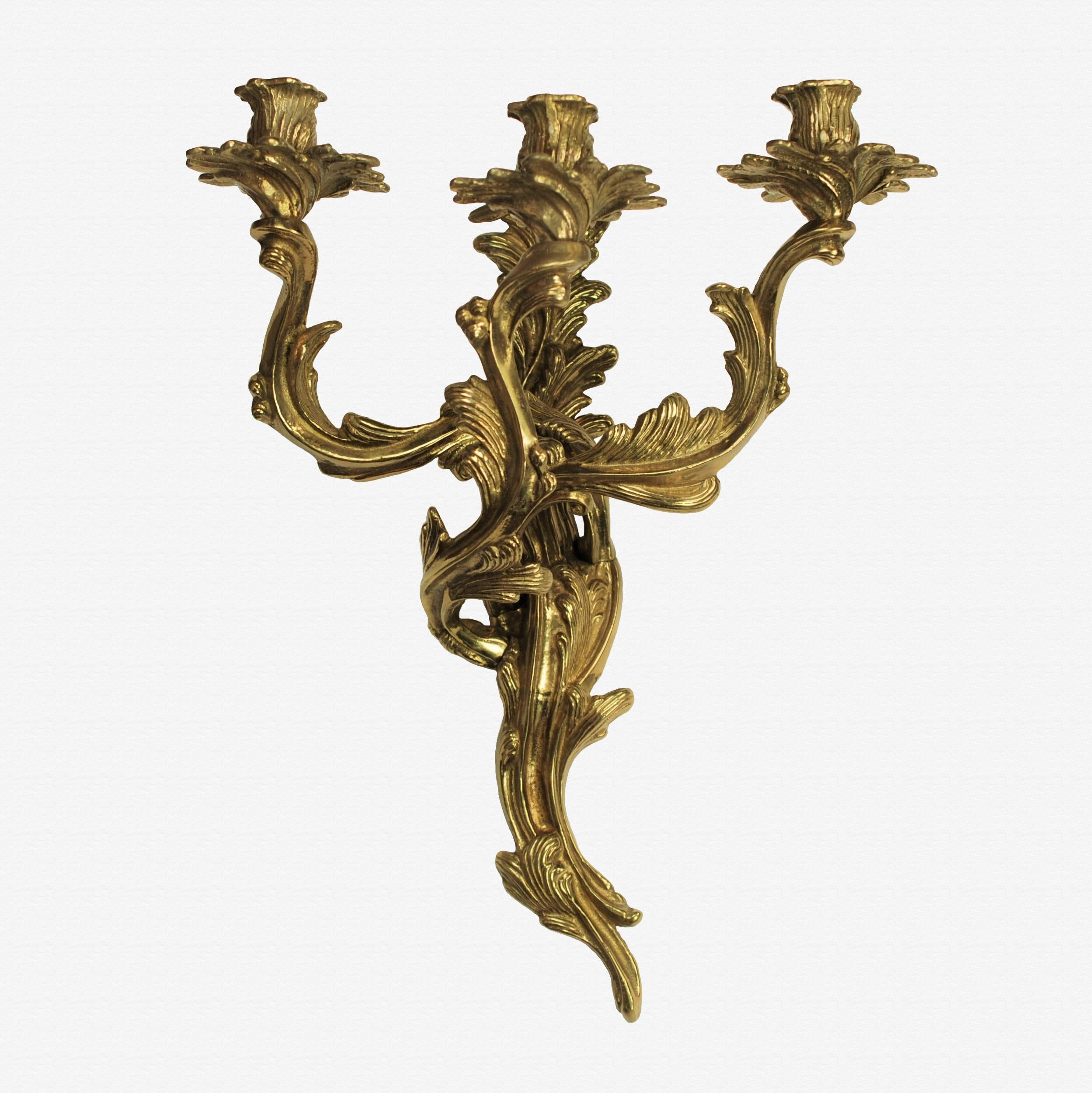 This elegant pair of Louis XV style cast brass sconces was made by Glo-Mar Artworks Inc of New York City. The pieces incorporate Rococo design elements and are reminiscent of the work of French silversmith François-Thomas Germain (1726-1791) as seen