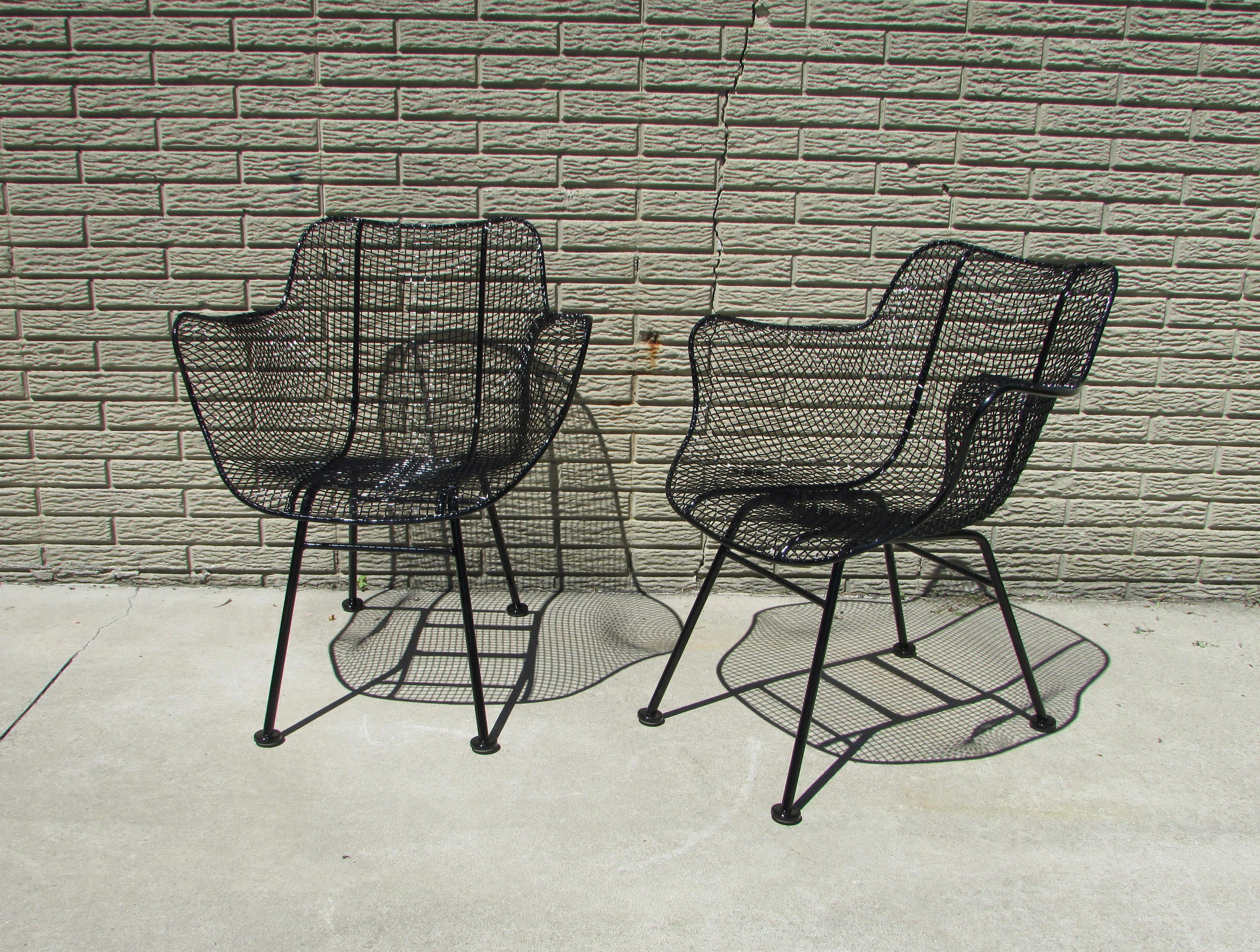 Pair of Woodard wrought iron framed chairs with steel wire mesh forming the seat and backrest . Recently disassembled powder coated in gloss black. New foot glides added as well.