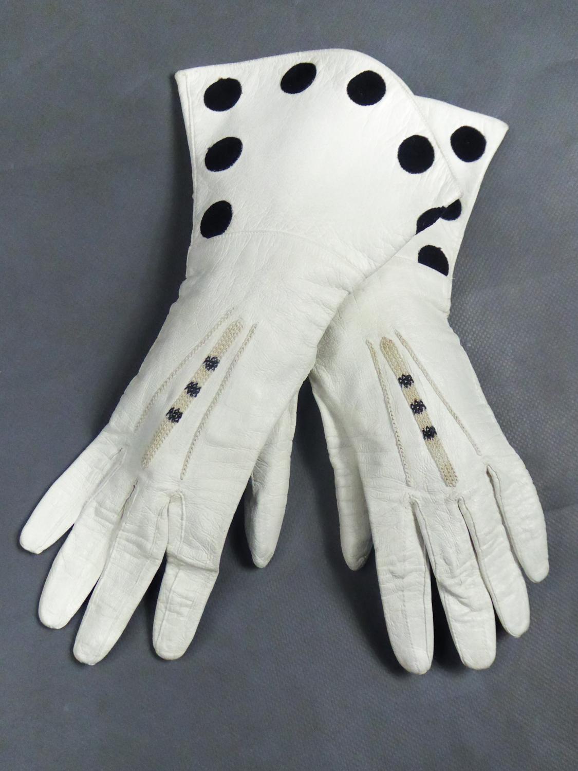 Um 1960
England

Schönes Paar zeremonieller Handschuhe aus weißem Sämischleder mit unleserlichem britischen Stempel auf der Innenseite, aus den 1960er Jahren. Elegante Stickerei aus schwarzen Baumwollkügelchen im Kettenstich. Wie neu, wahrscheinlich