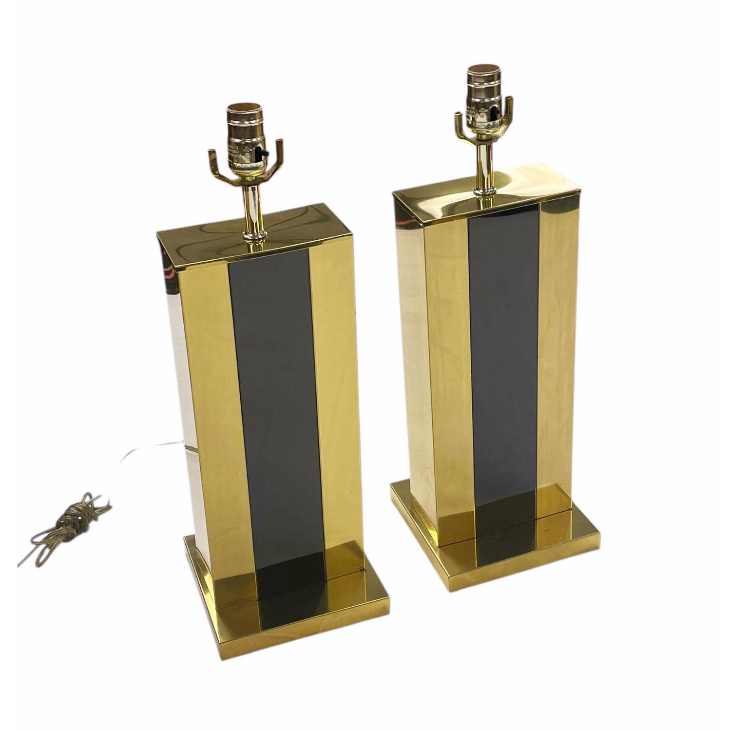 Coppia chic di lampade da tavolo in stile Pierre Cardin nere e oro. Le eleganti lampade non sono contrassegnate, ma sembrano essere di produzione italiana. Il metallo dorato scintillante è elegantemente accentuato da una banda nera al centro. Queste