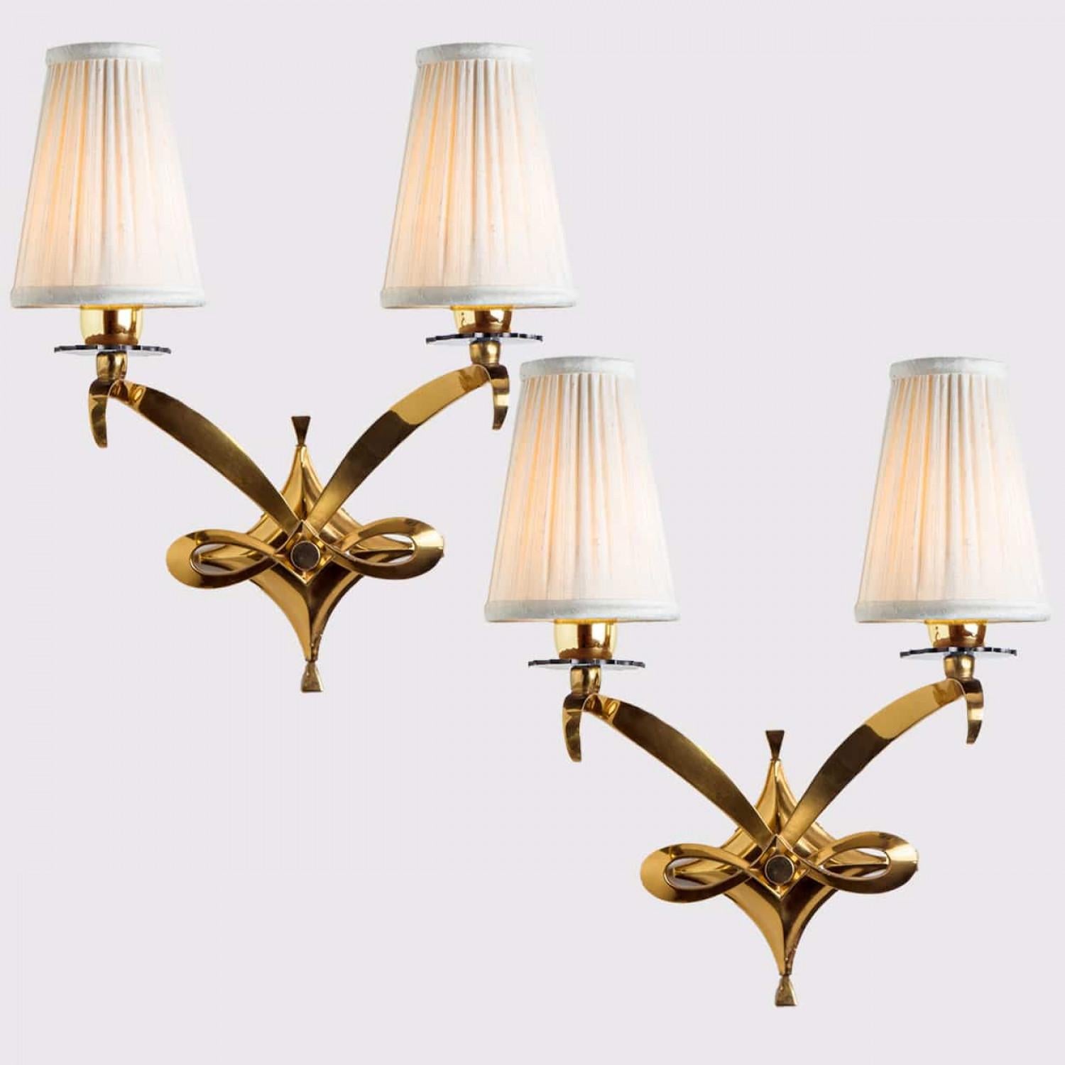 Applique Leleu in ottone regale. Ciascuna lampada è composta da aste dorate ricurve, con un paralume bianco in cima. Montato su una cornice in ottone placcato oro. Le aste rifrangono la luce in modo eccellente. Sono disponibili diverse opzioni in