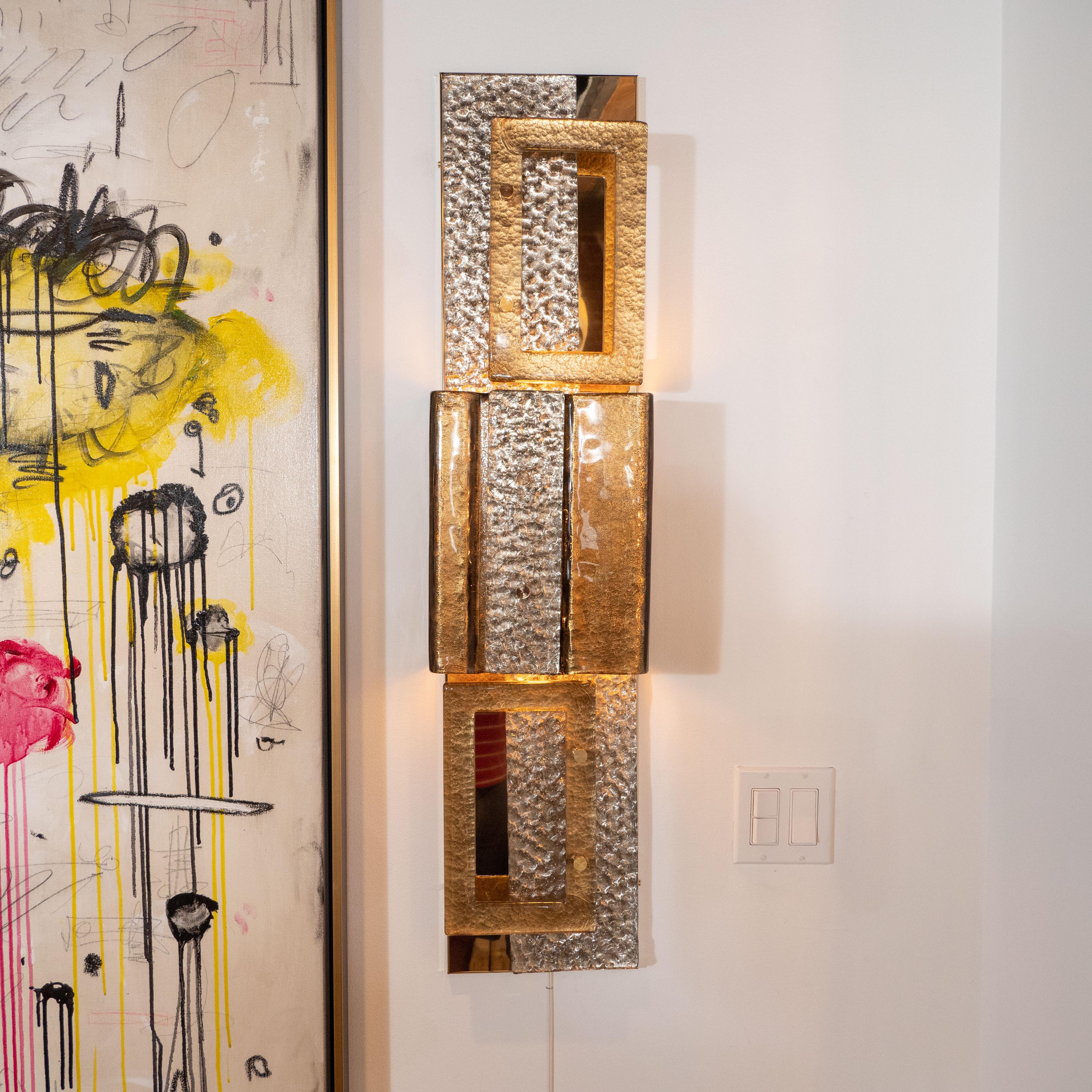 This impressively large pair of metallic gold and bronze Murano glass and brass sconces consists of three multi-stacked shimmering gold and bronze colored and textured glass and natural polished brass elements in various rectangular shapes. Each