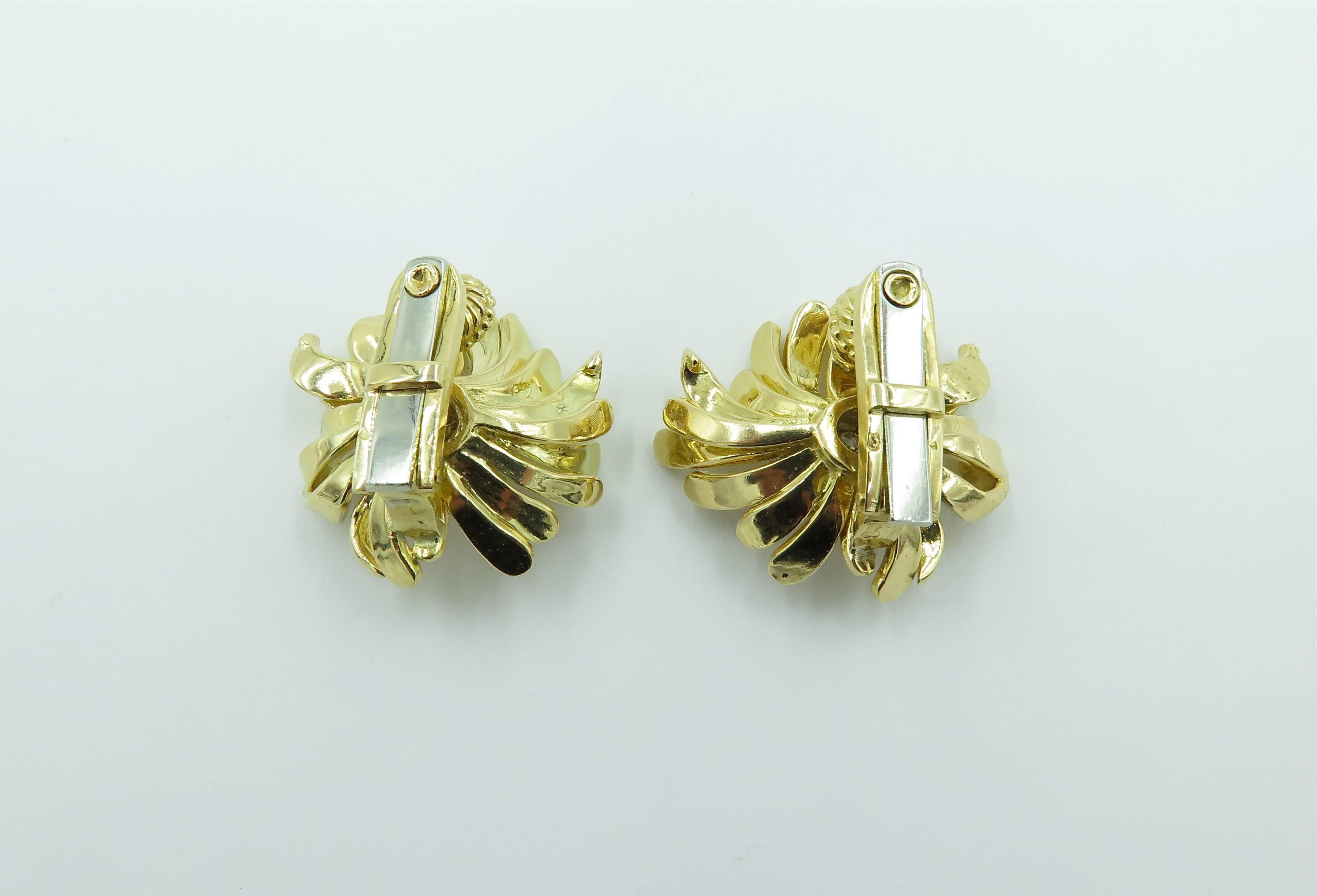 A pair of 18 karat yellow gold and diamond flower earrings. French. Circa 1960. Designed as a flowered, with textured gold undulating petals, centering a cluster of circular cut diamonds. Diamonds weigh approximately 1.40 carats. Diameter is