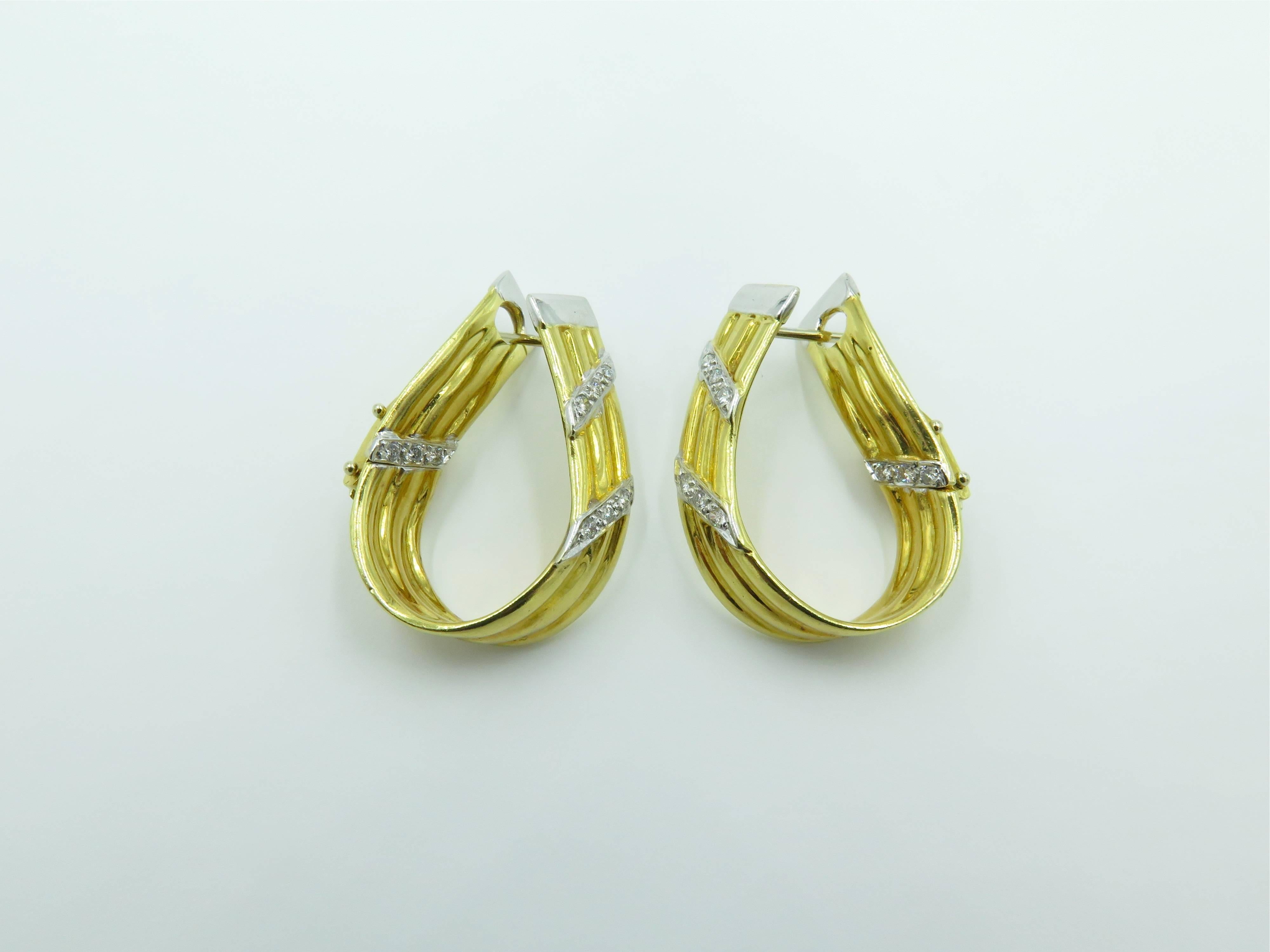 A pair of 18 karat yellow gold and diamond earrings, of elongate fluted hoop design, enhanced by lines of circular cut diamonds. Length is approximately 1 1/8 inches, gross weight is approximately 12.7 grams. 