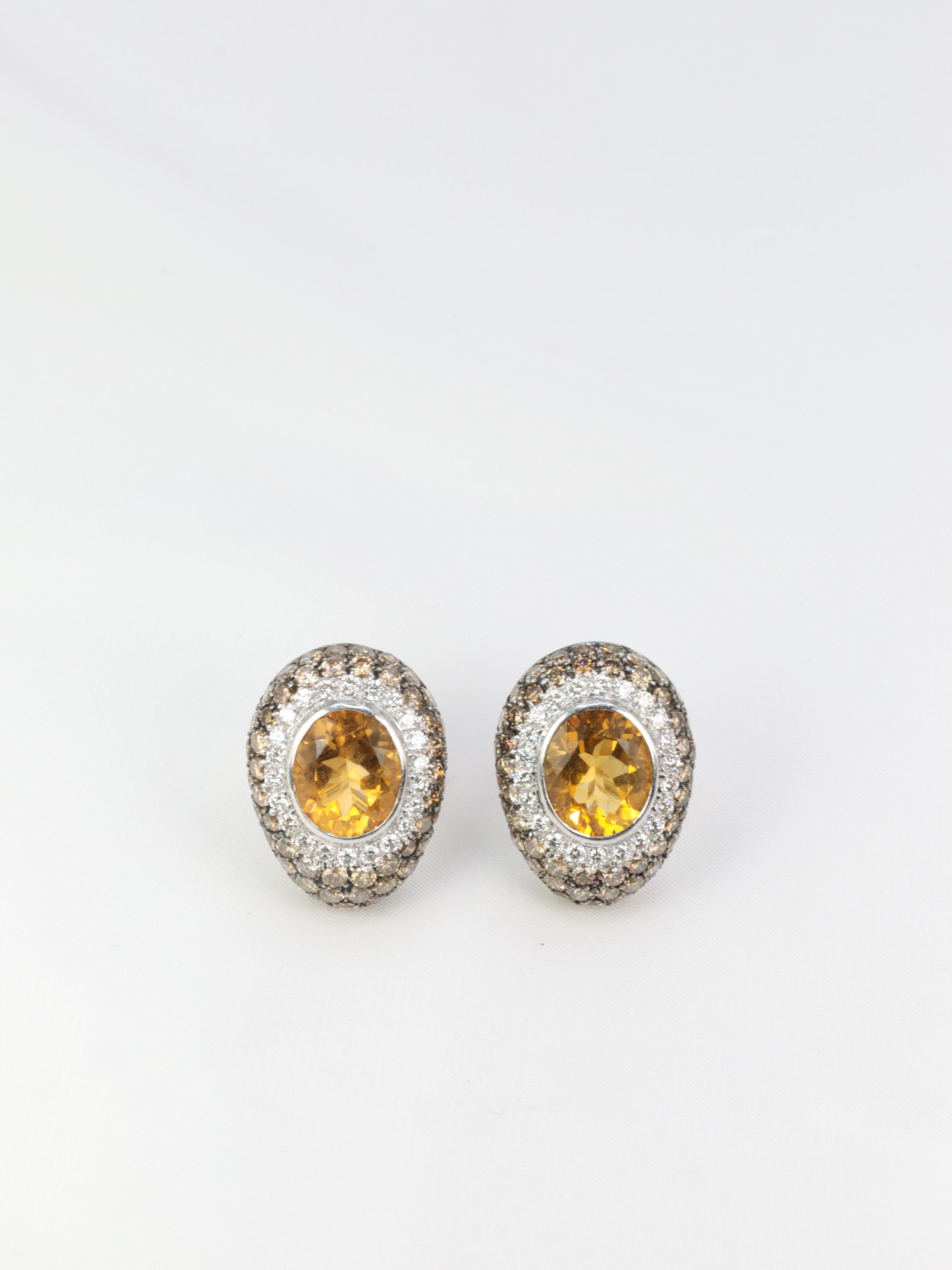 Very nice pair of ovoid ear clips in 18k gold (750°/°°) each set with an oval citrine weighing about 5 carats in a surround of white brilliant-cut diamonds of excellent quality for a weight of about 0.6ct and a pavement of champagne diamonds for a