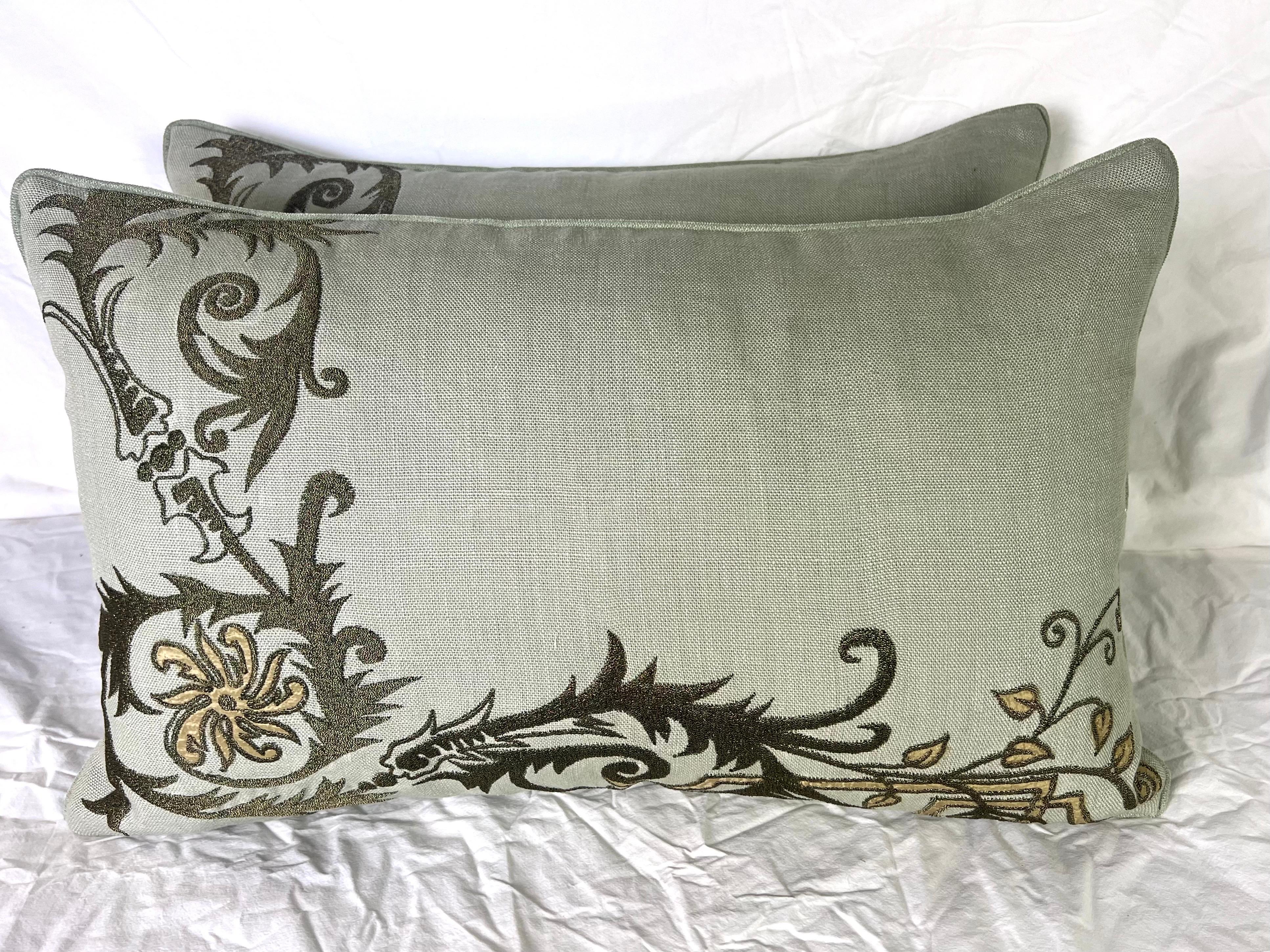 Coppia di cuscini personalizzati con un elegante lino ricamato da The Embroidery Palace.  Il ricamo presenta motivi floreali in oro antico metallizzato su un lino di colore naturale.  I bordi dei cuscini hanno un cordoncino che si abbina al lino