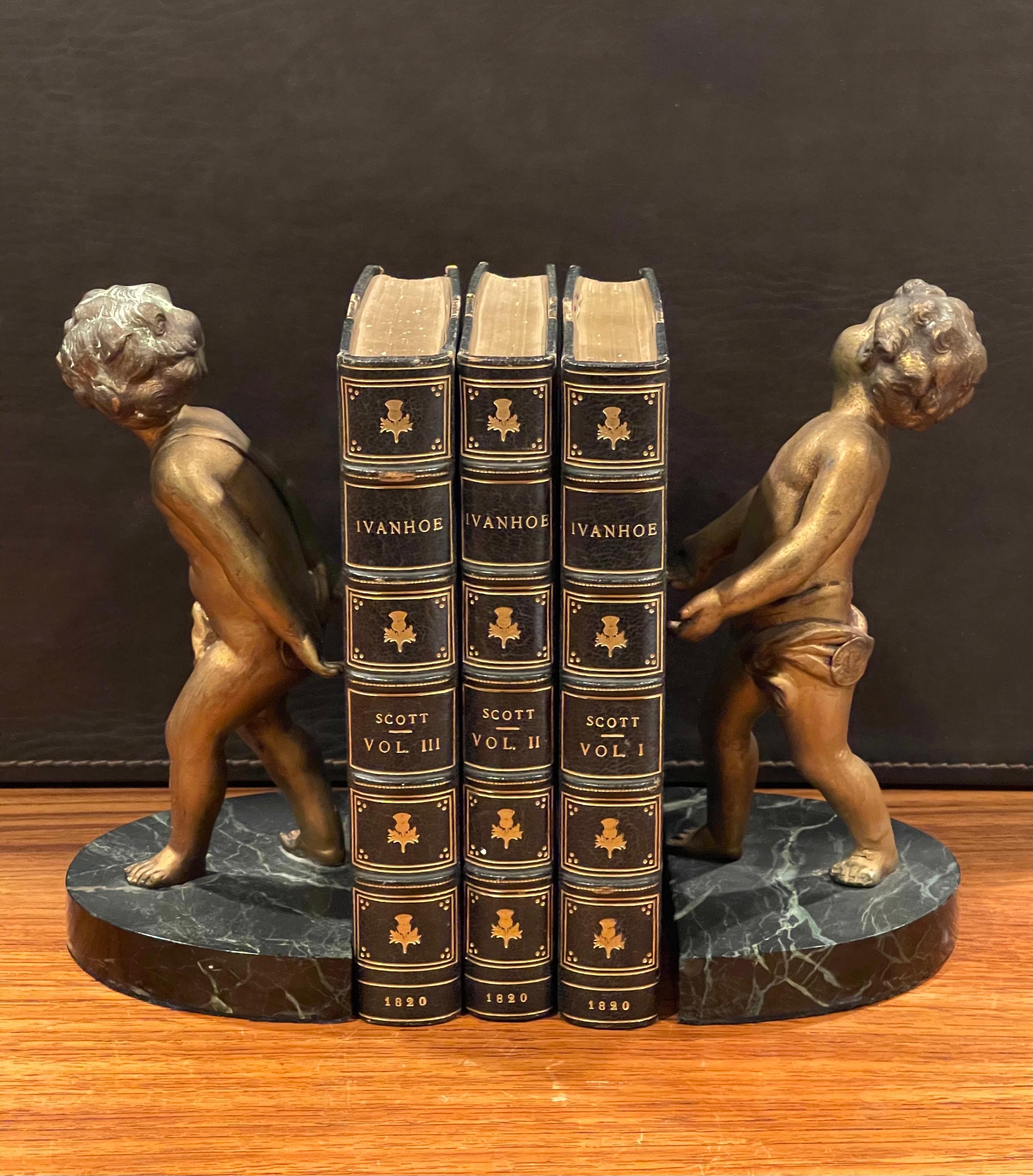 Gorgeous pair of gold gilt cherubs on a marble base Art Deco bookends from France, circa 1930s. They are in original condition with a fine patina, some light oxidation and some surface scratches; the pair measures 7.25
