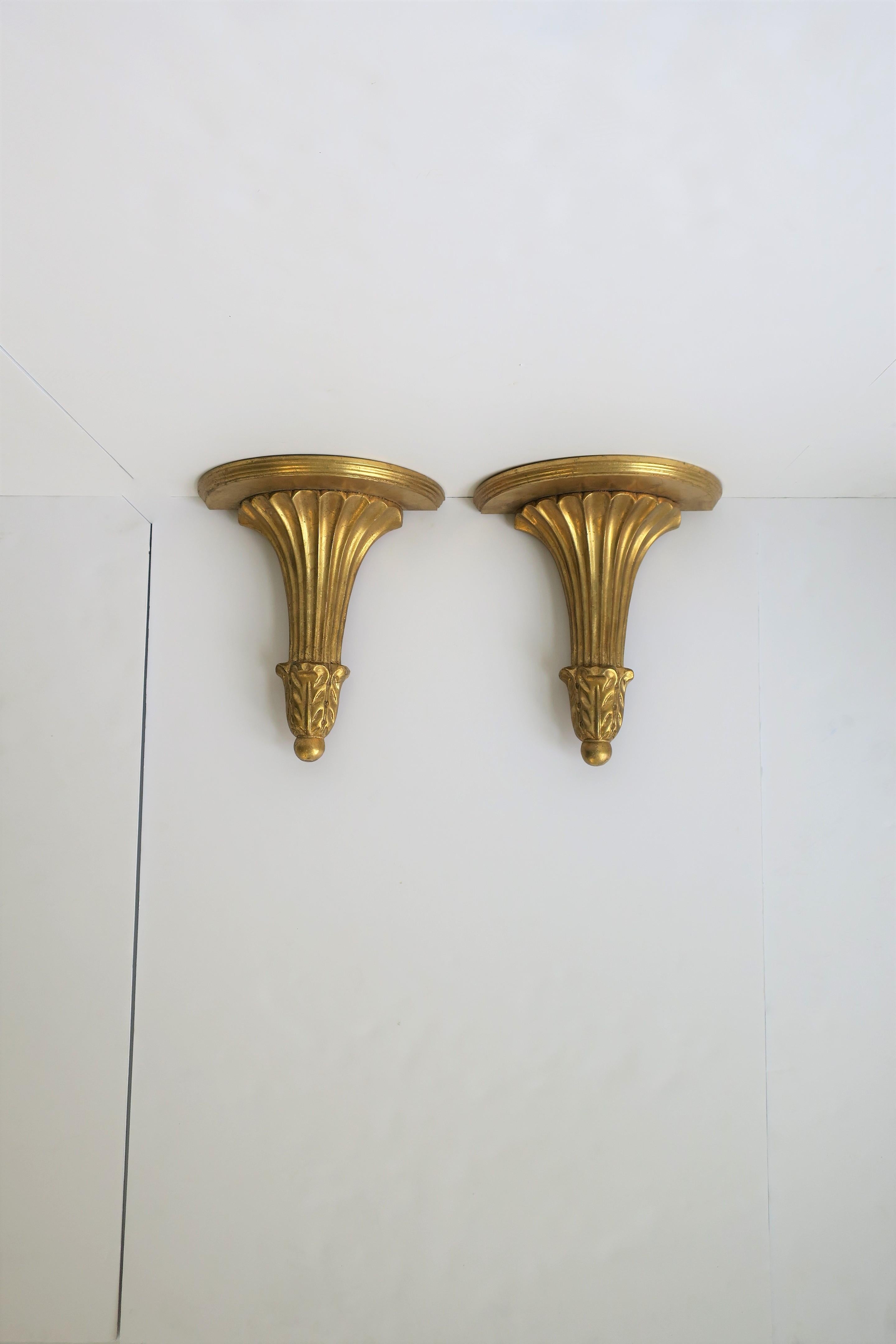 A beautiful pair of gold giltwood gold-leaf wall brackets or shelves with a pillar column design in the neoclassical style, circa late 20th century. Shelves may be Italian. 

Wall brackets/shelves each measure: 6.25