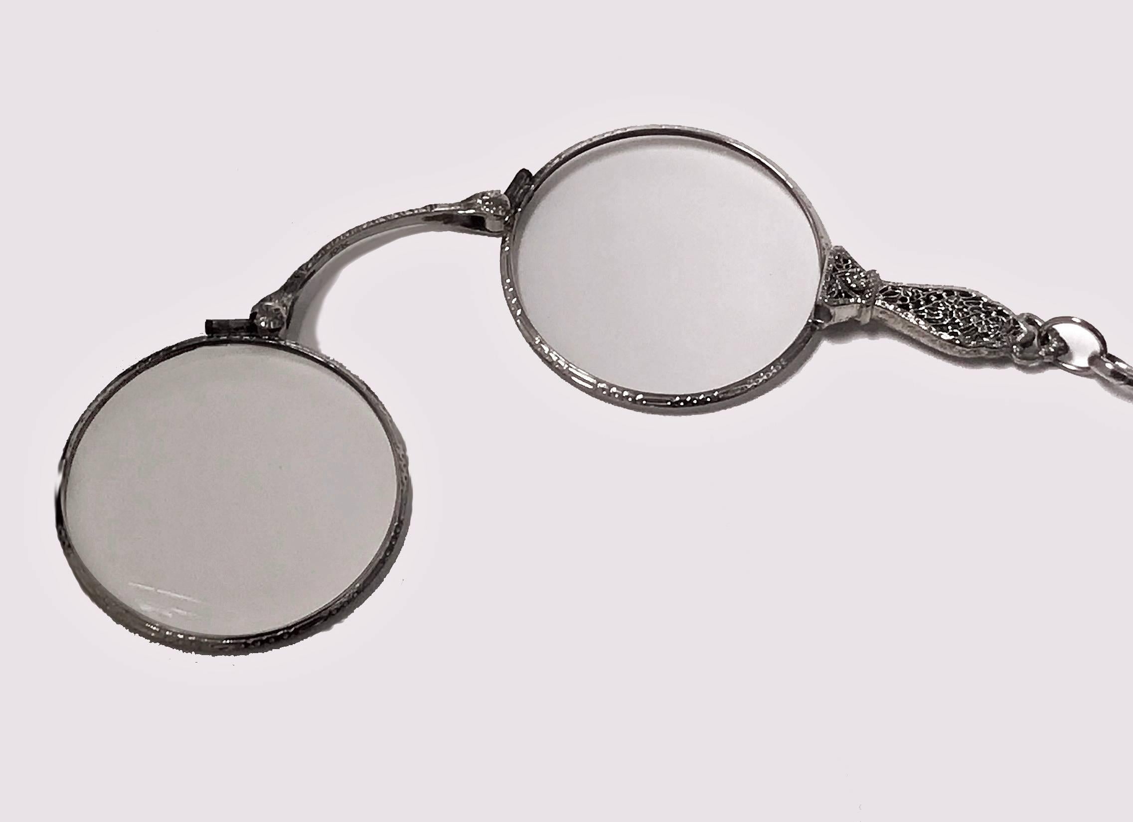 Pair of Gold Lorgnettes, C. 1920, 10K white gold, pierced filigree handle, engraved decoration surround to lenses, stamped 10K. Good spring mechanism, sturdy and fold nicely. Lenses unscrew to allow for different magnification. Open measurements: 4