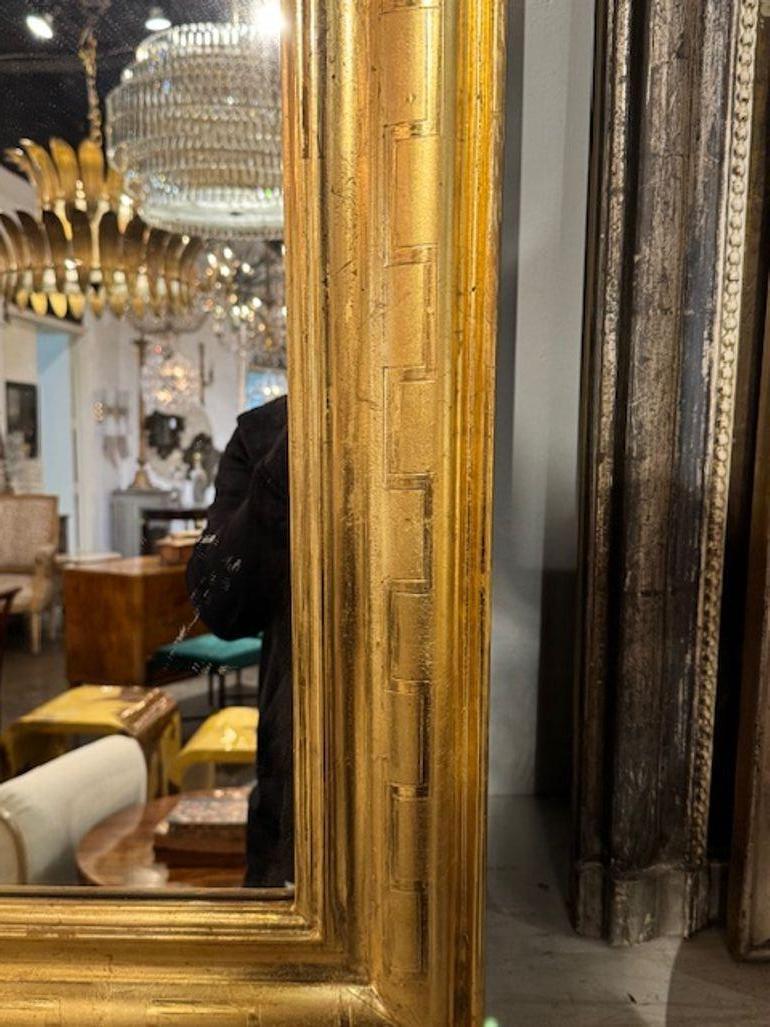 This pair of French Louis Philippe mirrors feature a geometric patterned frame made of wood. Beautiful gold patina and decorative pattern make them a stunning addition to any space. Perfect for those looking to add a touch of antique charm to their