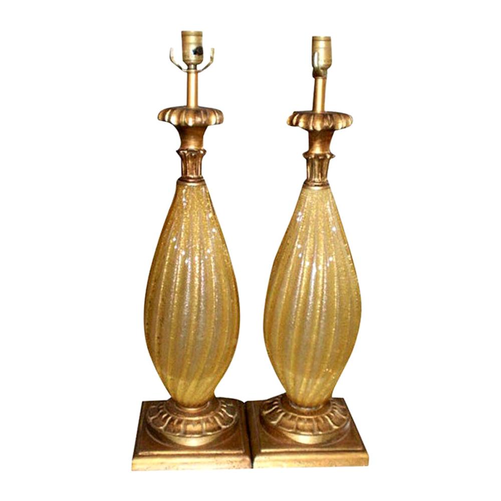 Gorgeous pair of vintage Murano glass lamps, gold with gold flecks on giltwood bases. This pair of Venetian glass lamps are in the style of Barovier. For a more modern look, these the bases on these Hollywood Regency Murano glass lamps could be