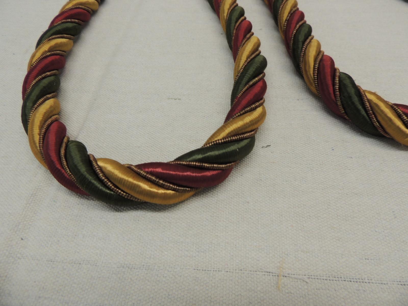 Pair of gold, red and green rope
Curtain holders/tie backs.
Silk curtain tie backs with holding loops
Size: 1” D x 32” L
(4” loops at both ends).
 