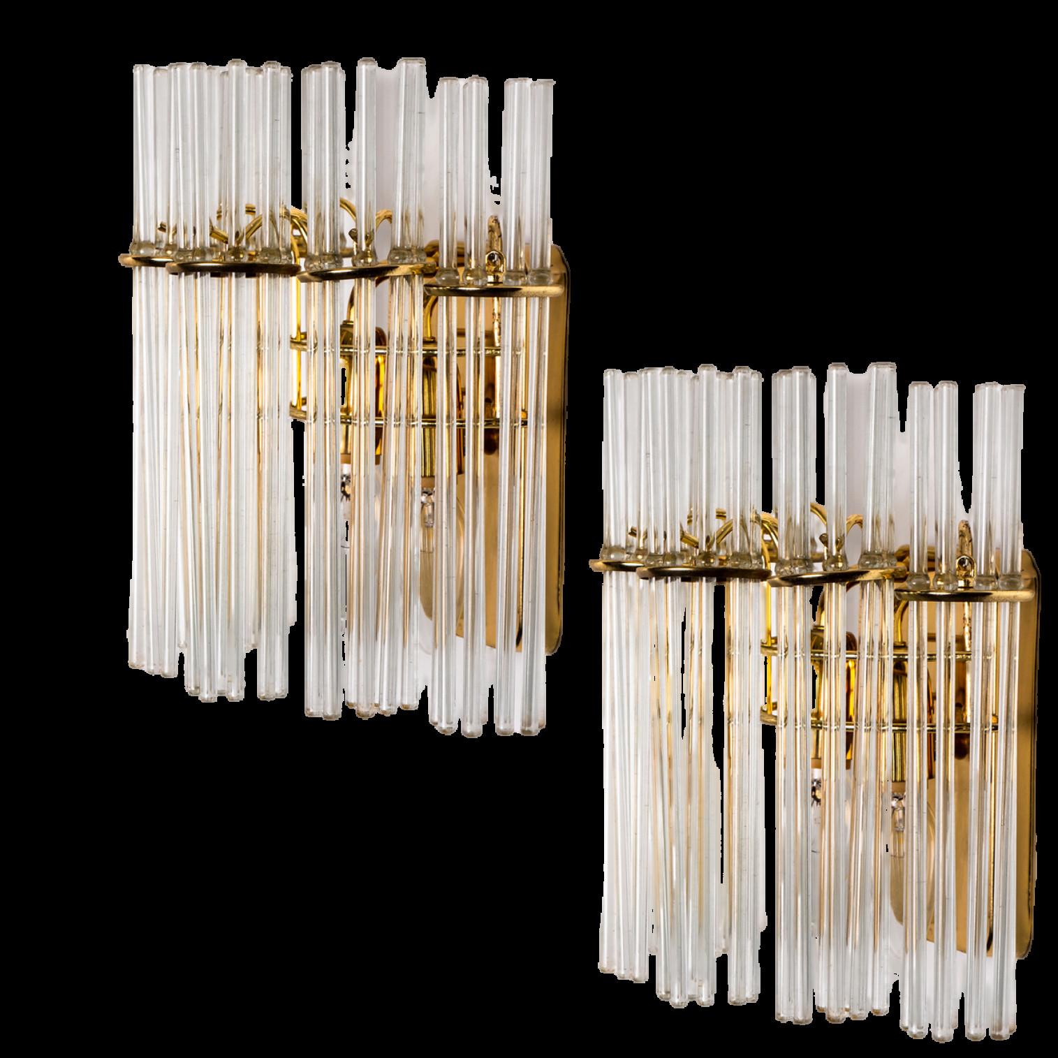 A wonderful pair of high-end wall sconces in the style of Sciolari. With long glass 'tubes' and brass details giving each piece an elegant appearance which refracts the light, filling a room with a soft, warm glow. The wall sconces have a brass back