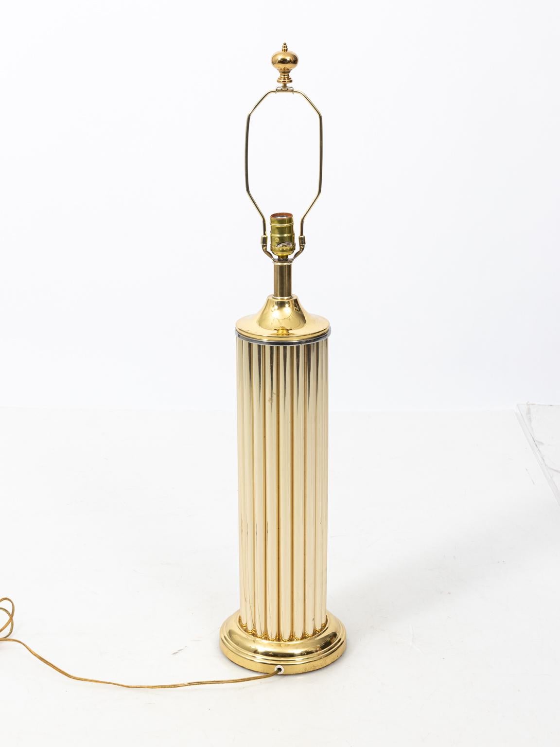 Midcentury pair of brass tone, composite lamps with fluted body on brass bases. The lamps also feature new linen cream drum shades with new brass finials. Shades not included.