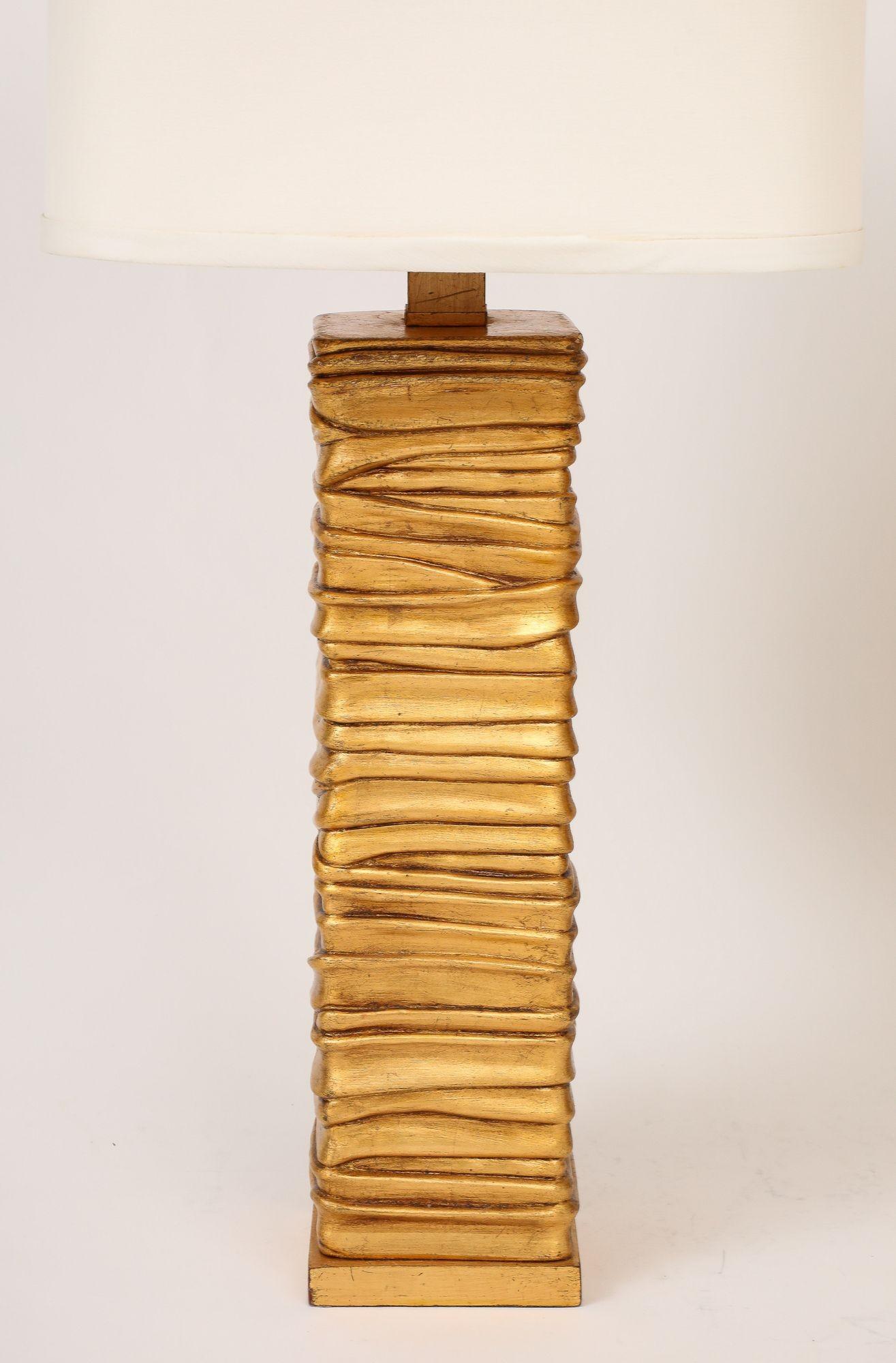 A wonderful pair of gold-tone lamps, each featuring a gracefully rippled column that beautifully marries the organic with the geometric. The textured surface catches the light, adding a subtle shimmer and depth. This thoughtful combination softens