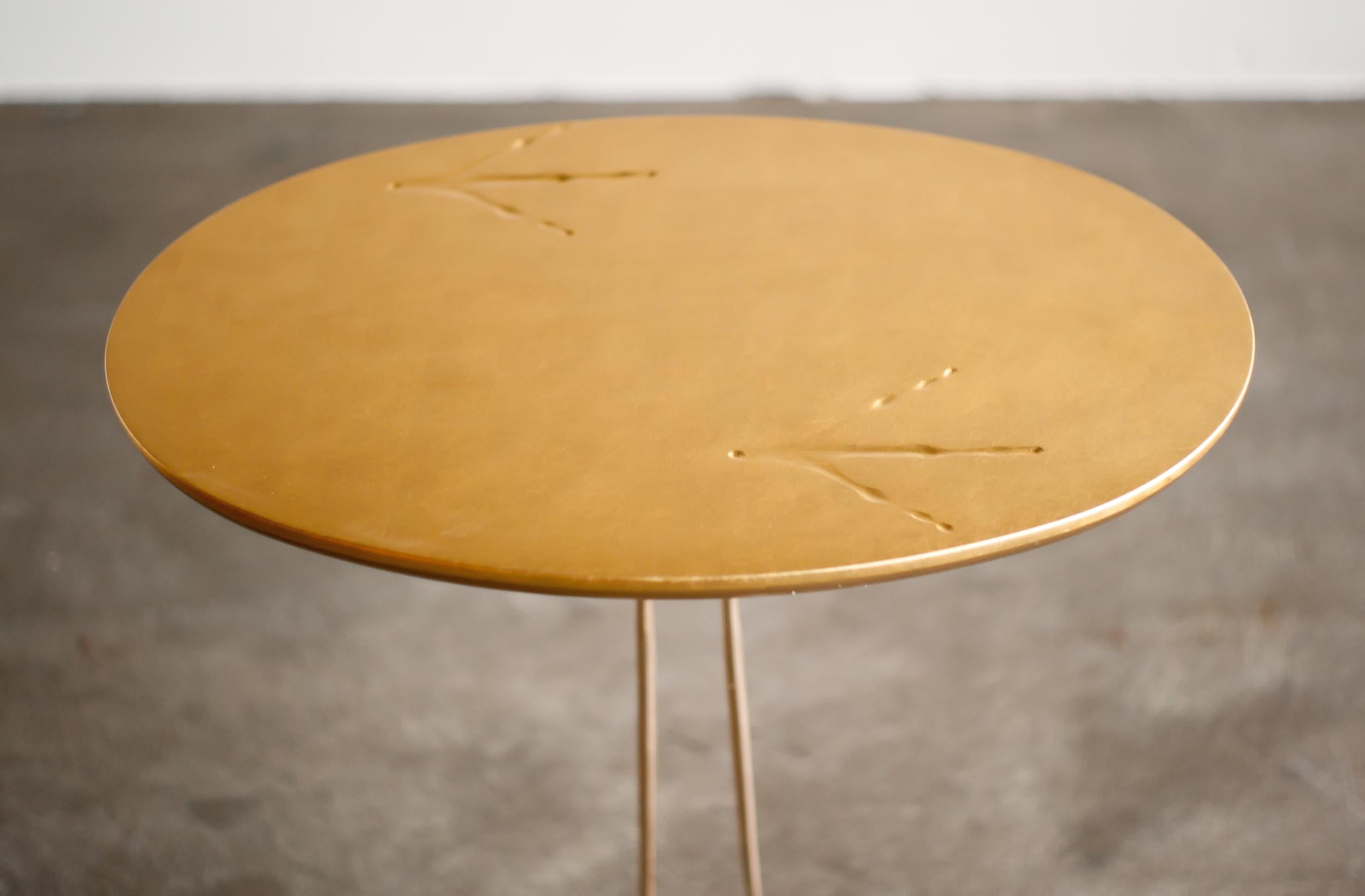 Pedestal tables Traccia by the Swiss designer Meret Oppenheim, Simon edition, Cassina. 
Serial production of the original 1939 Surrealist model.
Lacquered wooden top with 24-karat gold leaf. Polished cast bronze legs. 
Marked with label, they