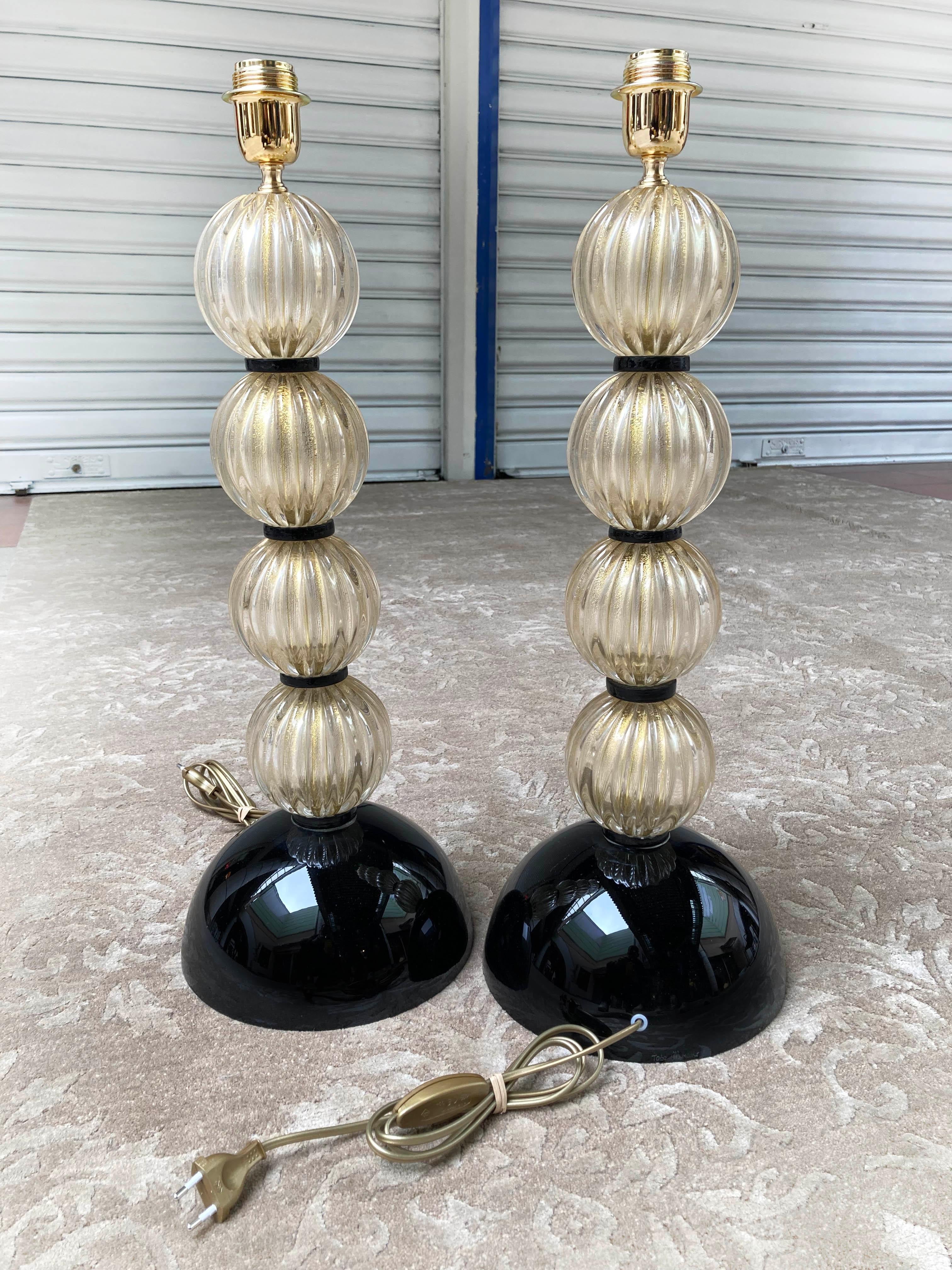 Pair of golden and black lamp bases - Signed Toso
Murano glass
Circa 1980
Measures: H 63 x D 23 cms
Signed at the foot
Shower feet with alternating ribbed glass spheres and smooth black glass pellets
In perfect condition / Electrical operation