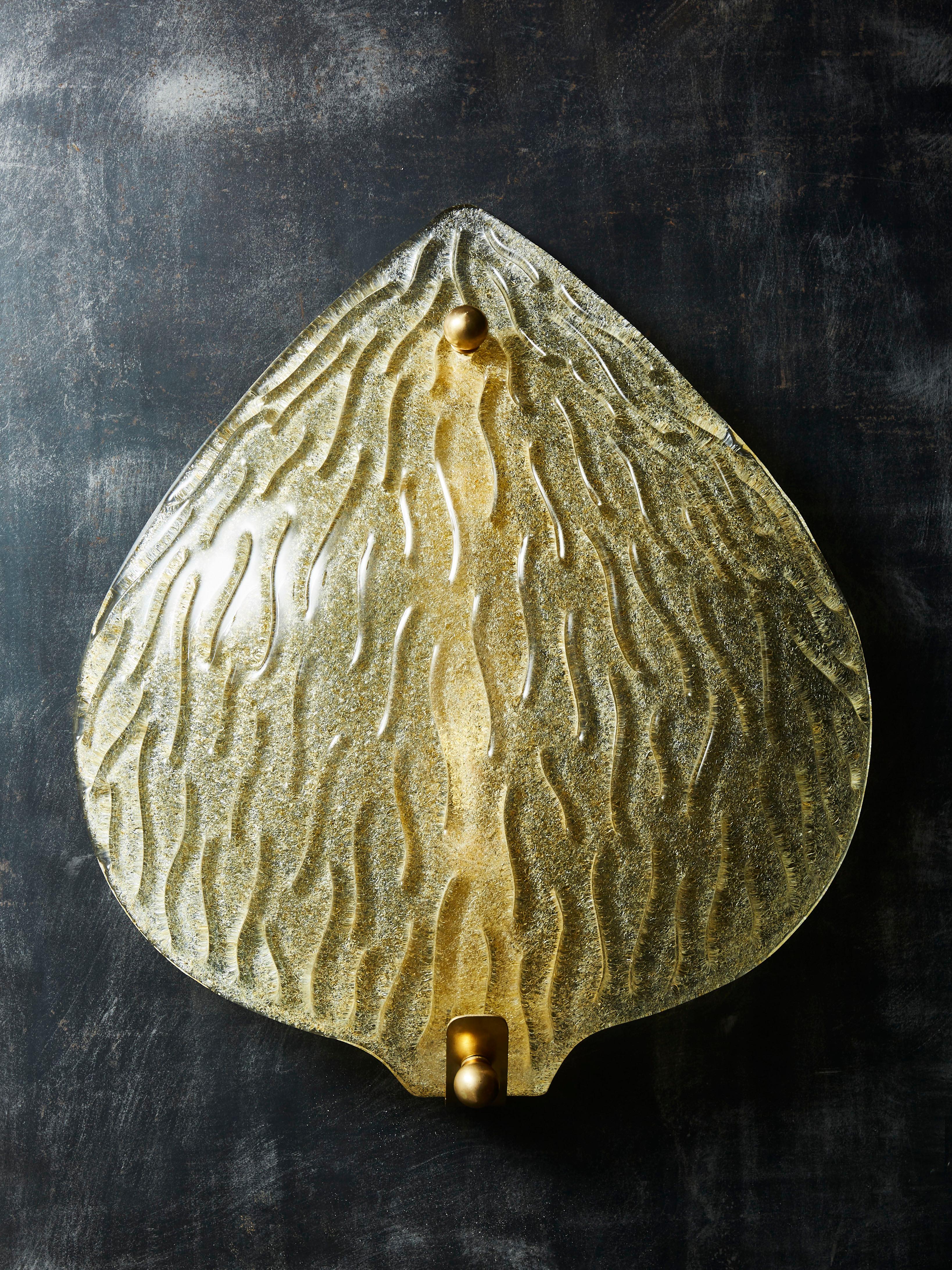 Pair of wall sconces made of a brass structure covered with a big golden Murano glass leaf.
