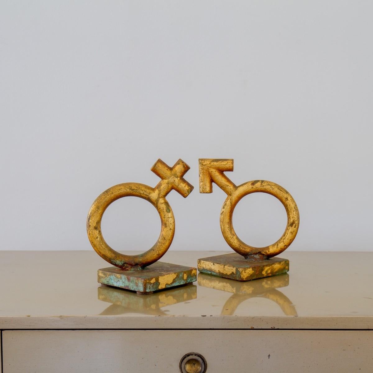 A pair of very tarnished gold leaf cast metal bookends depicting the Mars and Venus gender symbols by Curtis Jere signed and dated 1969.

Curtis Jeré is the collaboration of two metal sculptors Jerry Fels and Curtis Freiler who founded the company