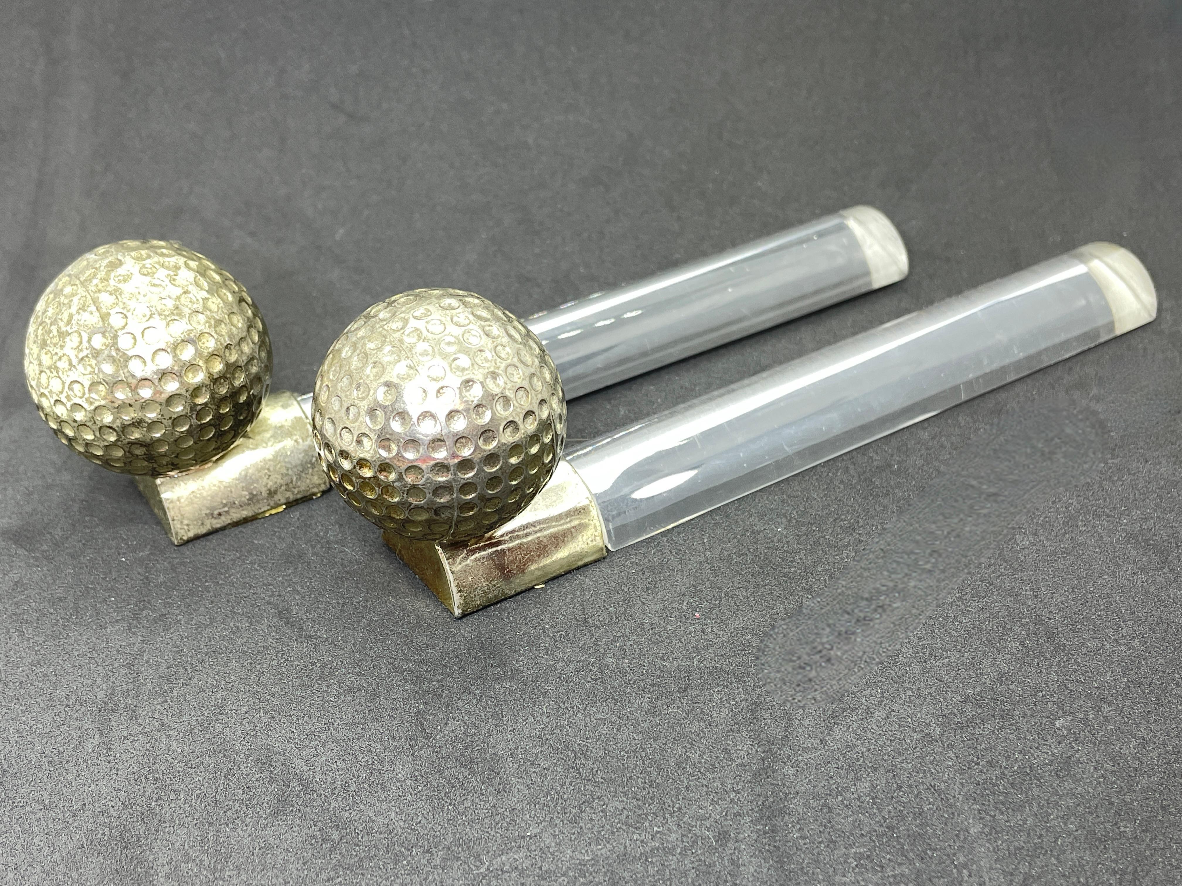 Super cool and nice design sculptural golf ball bookends. Nice golfball atop a nickel base. Nice addition to every room. Chrome with patina and one of the lucite stands with scratches like seen in the pictures. Think they will look great in a man