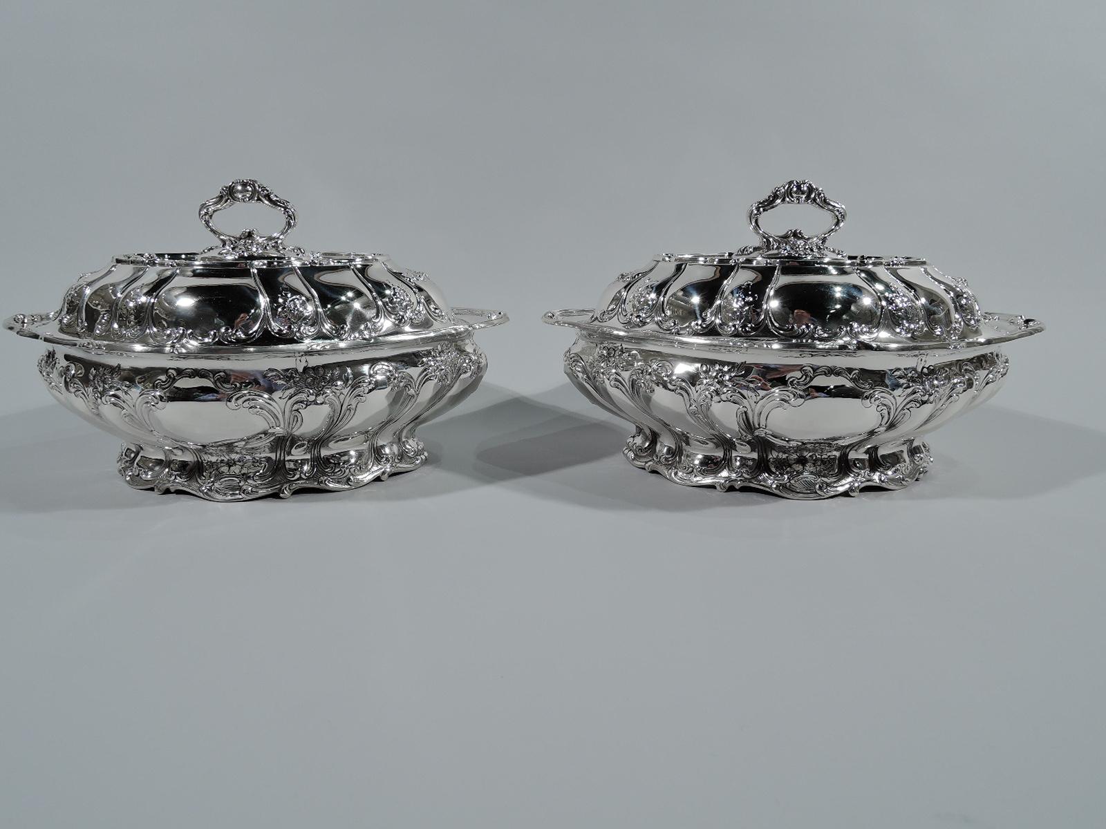 Pair of Chantilly sterling silver covered vegetable dishes. Made by Gorham in Providence in 1899. Each: Bellied lozenge bowl with scrolled everted rim and raised ovalish foot. Raised cover with twist-lock scrolled ring handle for conversion to
