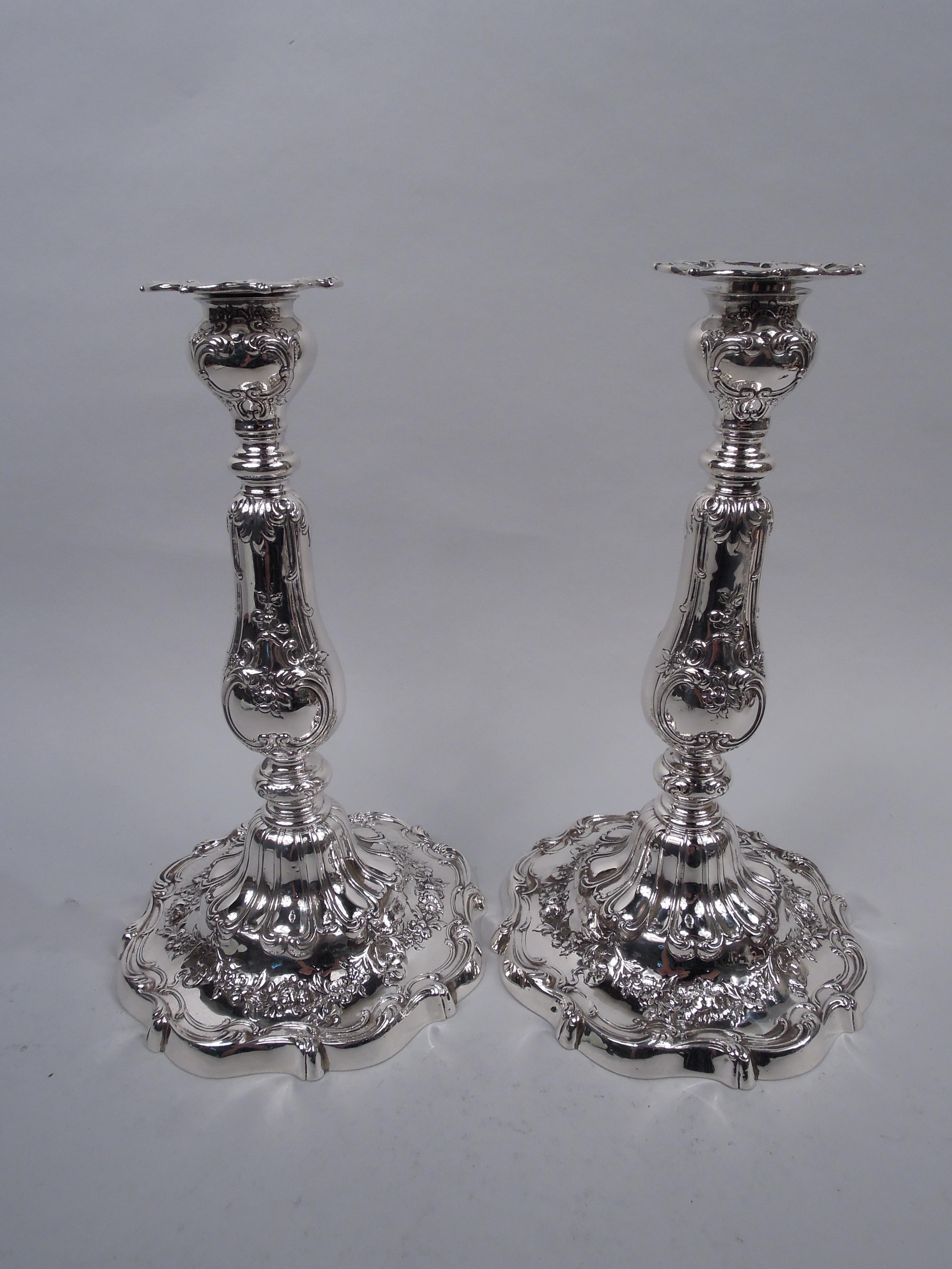 Pair of Edwardian Classical sterling silver candlesticks. Made by Gorham in Providence in 1914. Each: Ovoid socket with detachable bobeche on knopped baluster shaft; domed foot. Fancy floral garlands, gadroons, leaves, and scrolls. Scrolled rims.