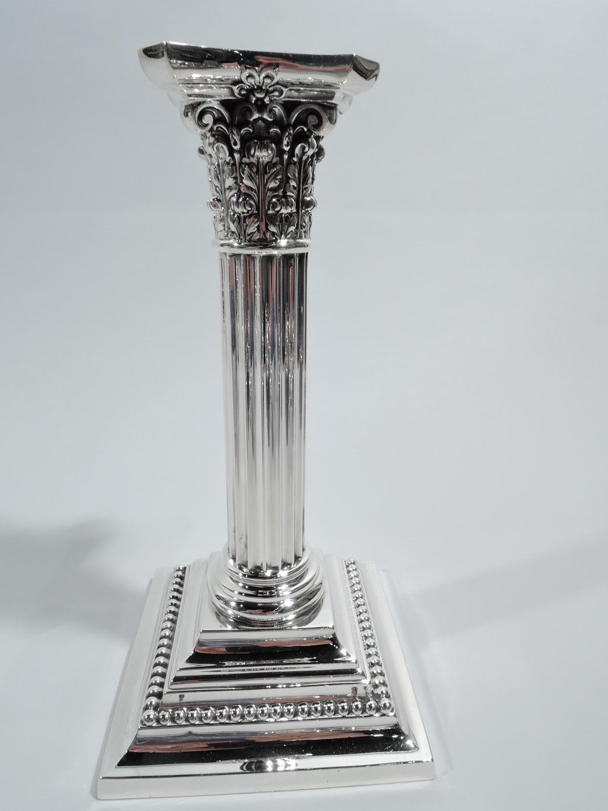 Pair of Edwardian Classical sterling silver column candlesticks. Made by Gorham in Providence in 1909. Each: Column with fluted shaft on stepped square base. Corinthian capital with chamfered and concave bobeche. Beading. Fully marked including