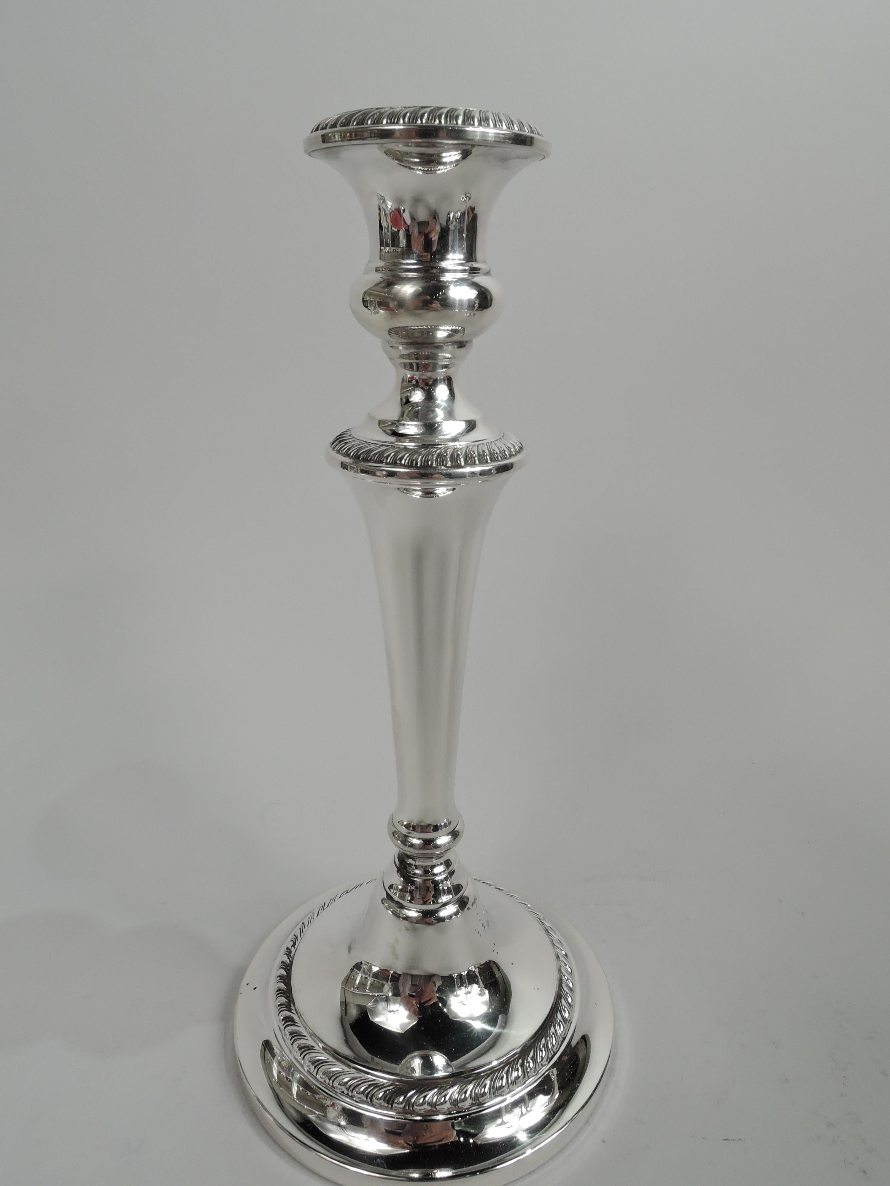 Pair of Modern Georgian sterling silver candlesticks. Made by Gorham in Providence. Each: Bellied socket on tapering columnar shaft with base knop and domed foot. Gadrooning. Fully marked including maker’s stamp and no. 670. Weighted.