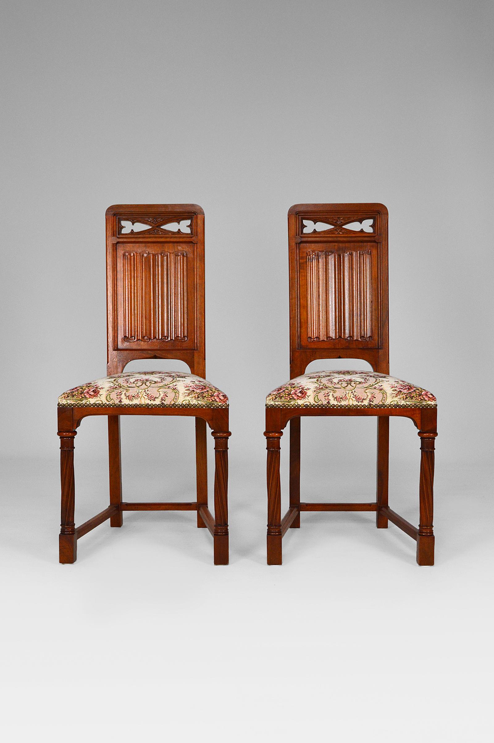 Pair of caquetoire / side chairs in walnut with carved scroll backs, and beige and pink floral patterned fabric.

Neo / Revival Gothic Renaissance style, France, around 1890.

Structure in perfect condition, seat fabrics in used