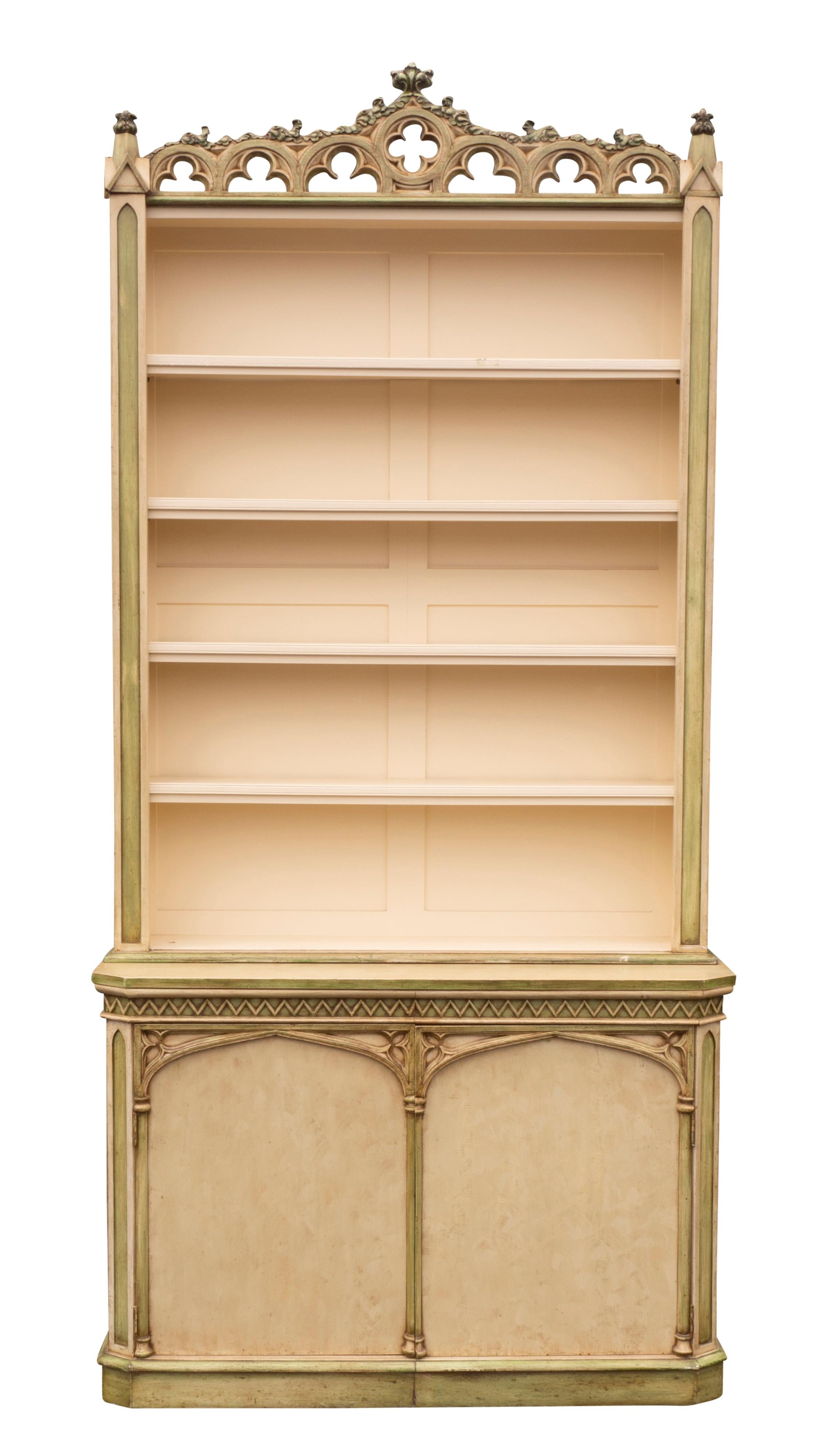 One 4.25 inches wider than the other. Each with a pierced and carved gothic cornice over an open bookcase with four adjustable shelves. The base with a carved frieze with sawtooth design and a pair of gothic design paneled doors opening to shelving.