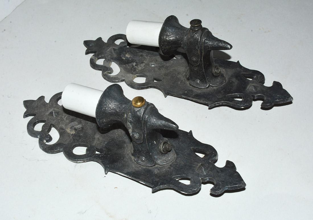 The pair of antique sconces have cast iron filigree shields and light sockets. Wired for US electrical use and regular light bulbs. The sconces, with their rustic finish, would look well on a porch or in a sun room.