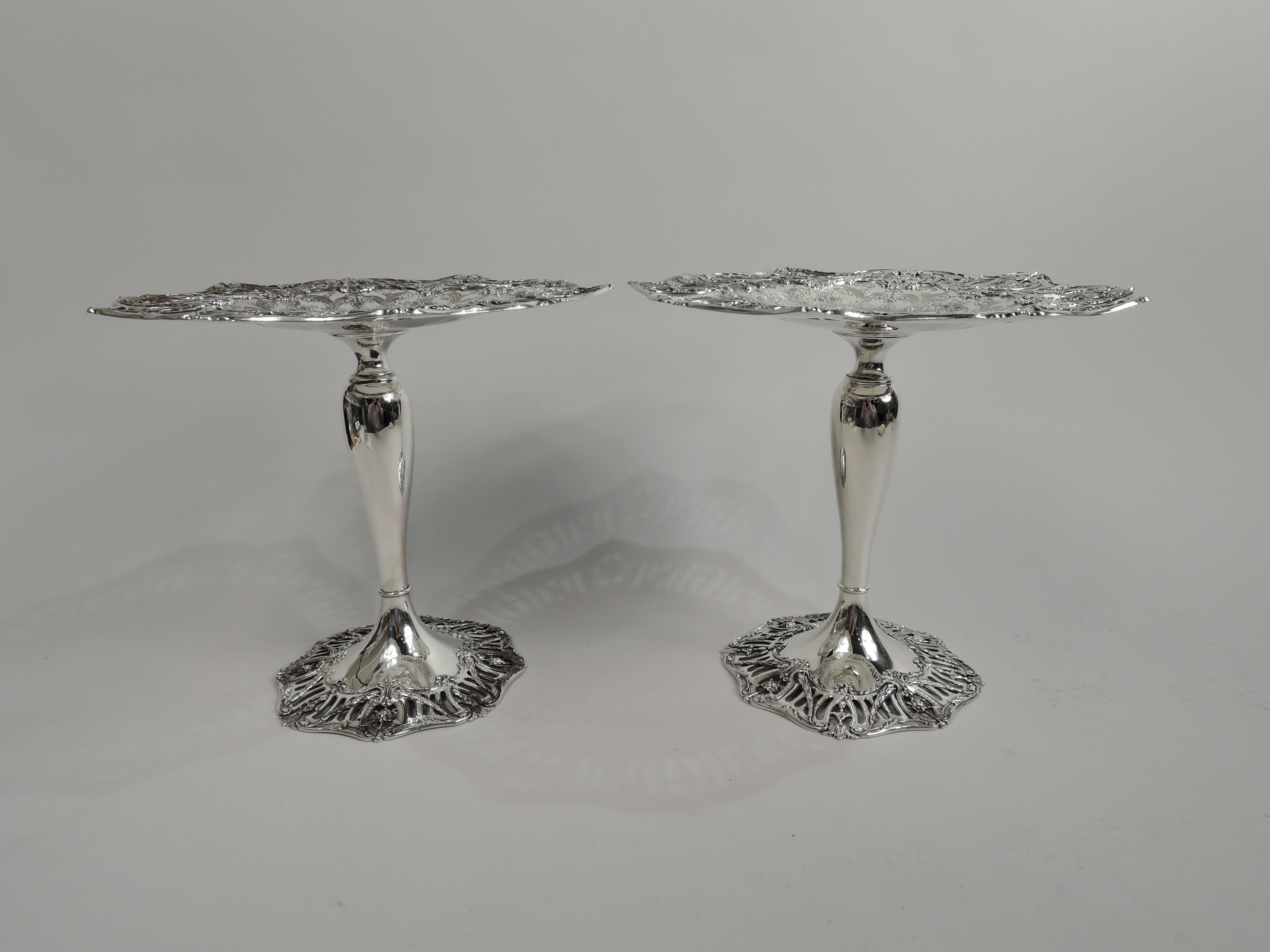 Pair of Edwardian Regency sterling silver compotes. Made by Graff, Washbourne & Dunn in New York, ca 1909. Each: Round and shallow well bordered by engraved scrolls, leaves, and flowers; center vacant. Baluster shaft with base knop and raised foot.