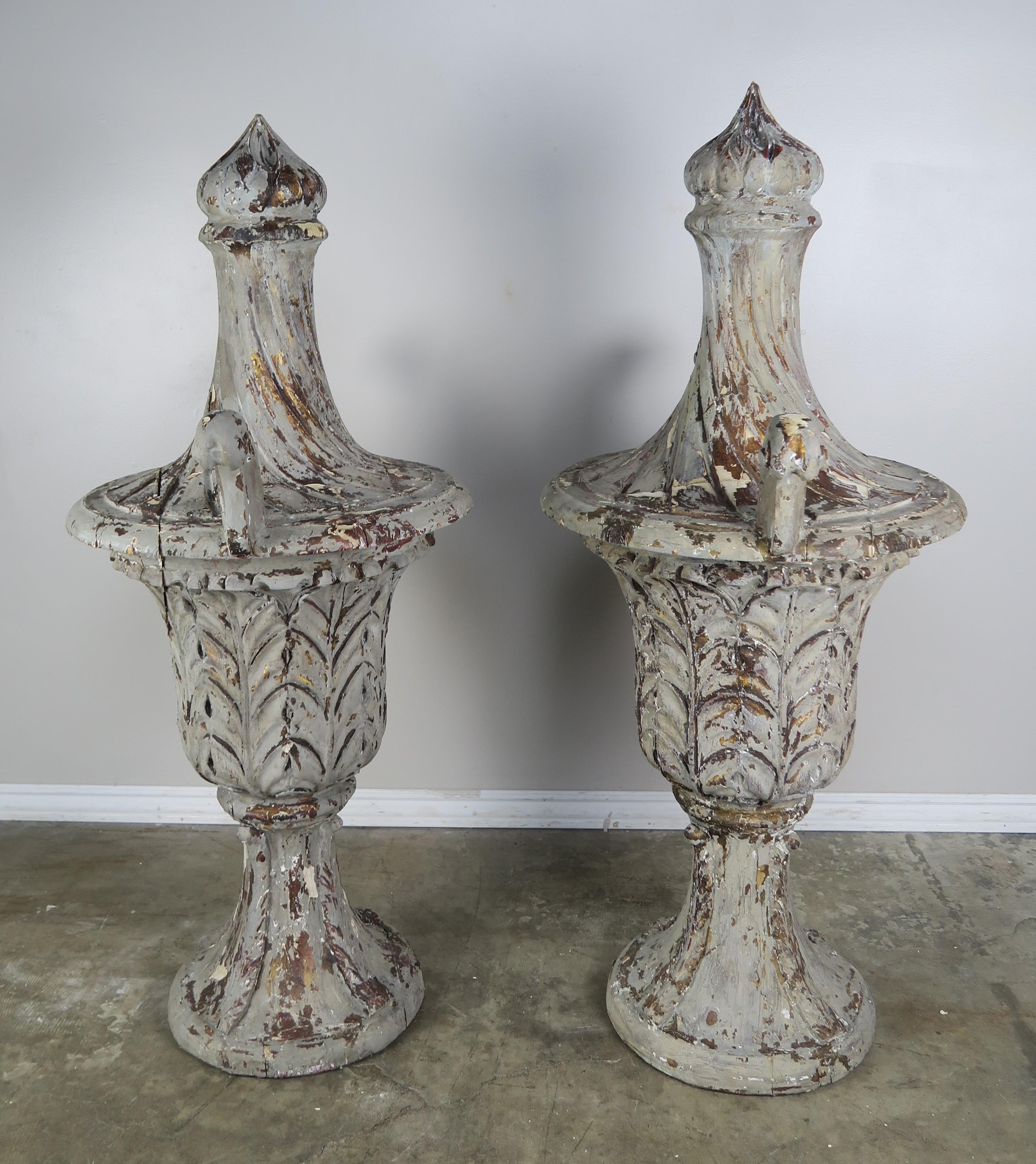 Pair of grand size carved wood flamed finial urns with two arms. The urns have a beautiful worn grey painted finish with natural wood exposed underneath the distressed paint.