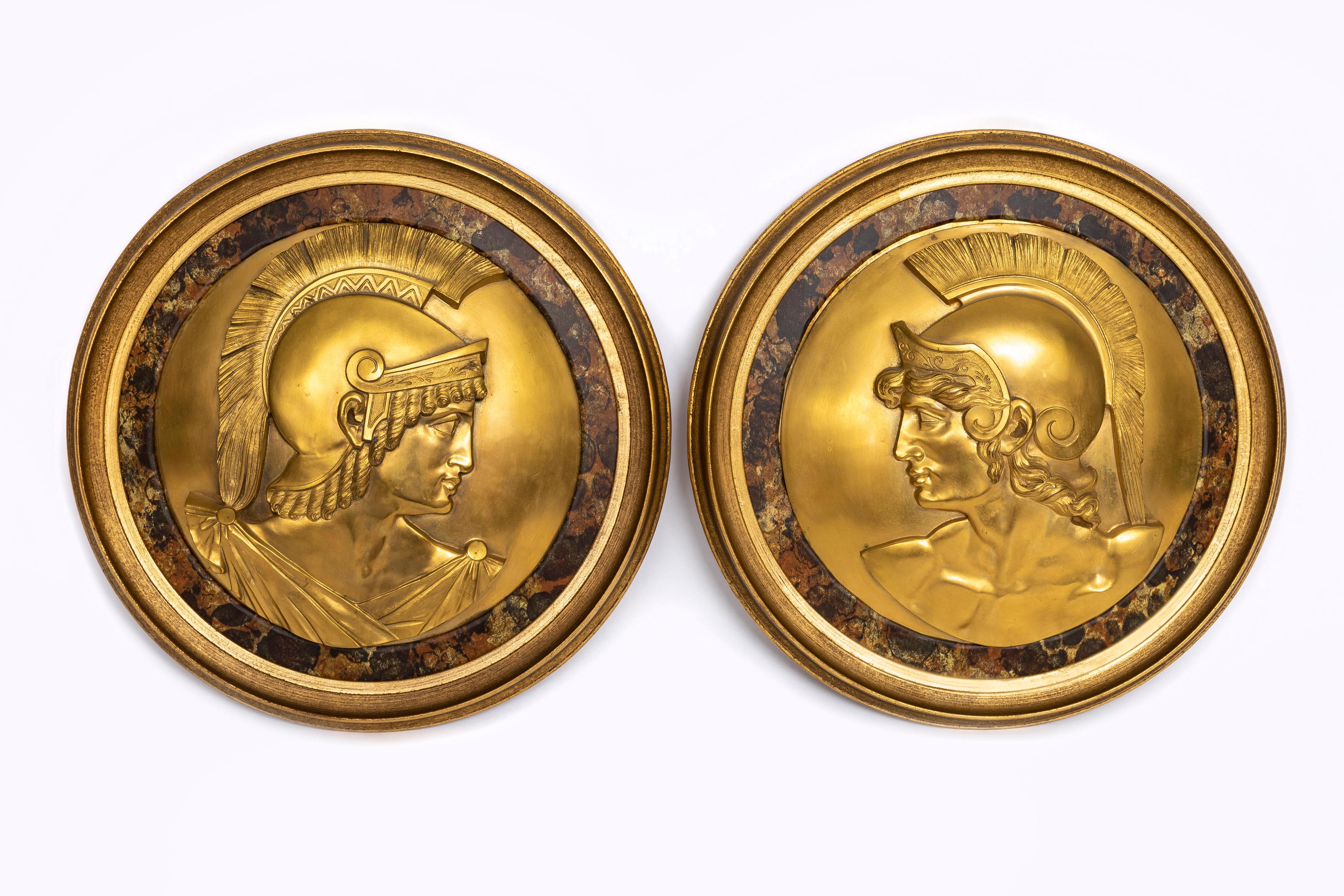 Fantástico par de placas de gladiadores romanos en bronce dorado del siglo XIX con bordes de mármol de imitación.  Cada marco está bellamente tallado a mano y los medallones de bronce están en altorrelieve y representan a soldados romanos con casco