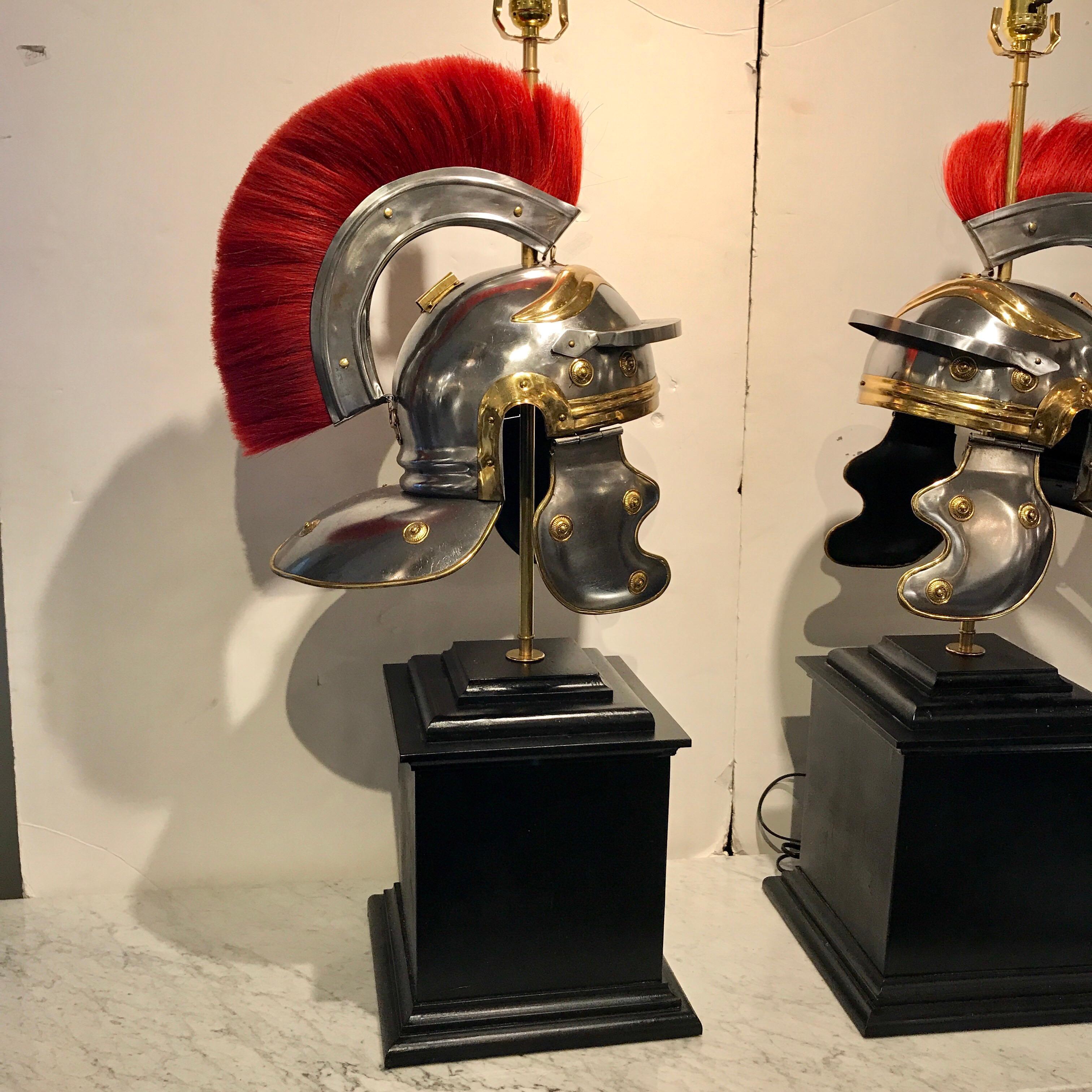 A pair of Grand Tour steel and brass Roman helmets, now as lamps. Each one with red plume on a realistically modelled Roman helmet made of polished and satin steel, with brass mounts. Raised on 12-inch square ebonized wood pedestal bases.
The